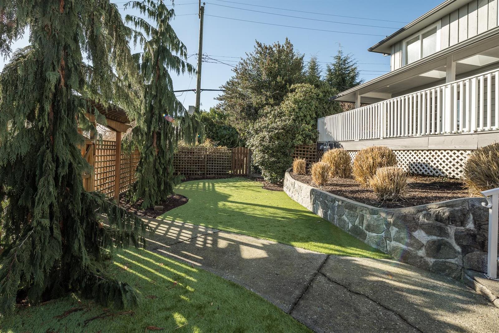 The lawn beside the house, a stone wall holding the grade.