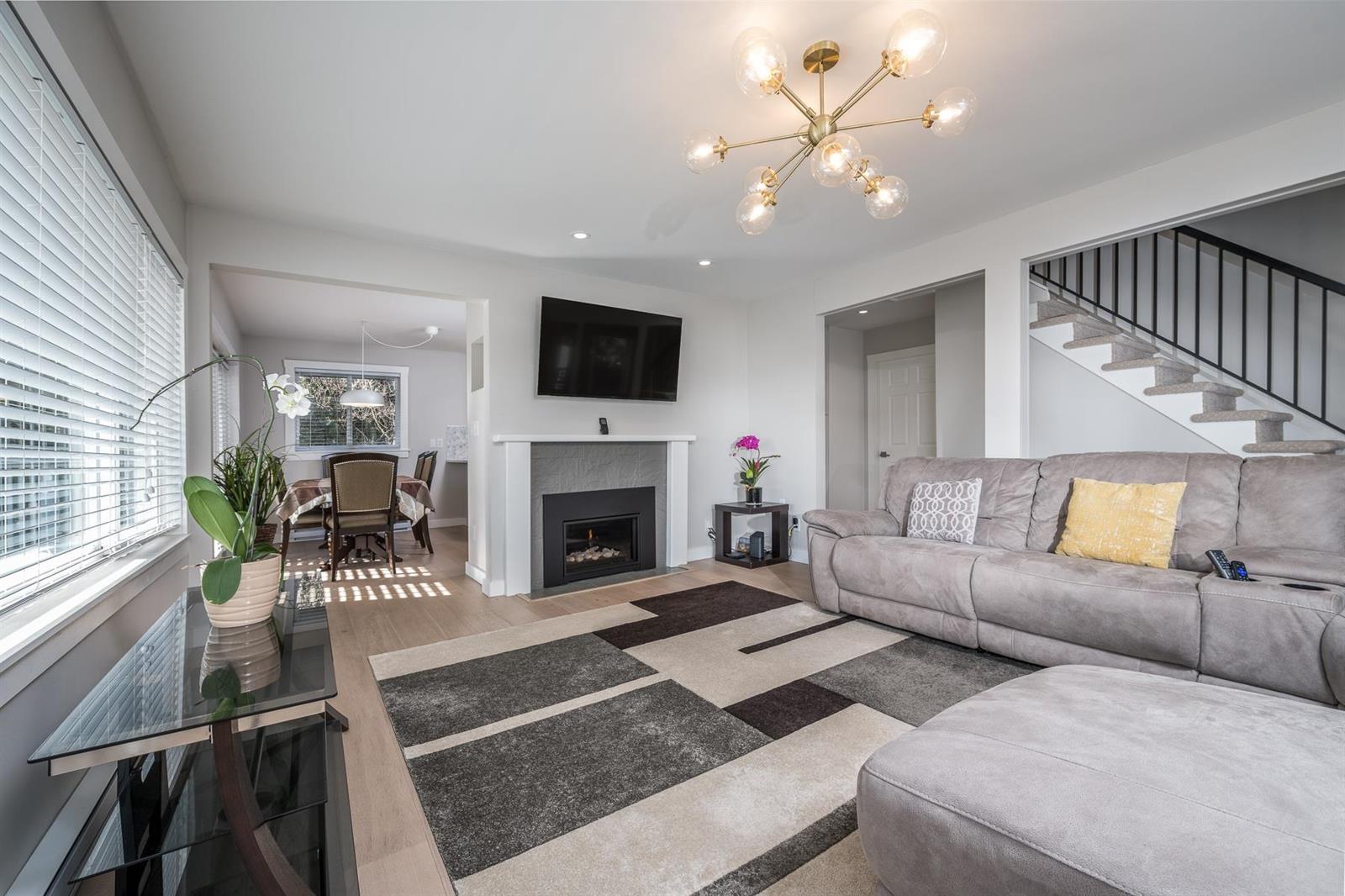 The living room, a sectional facing the fireplace with the stair behind.