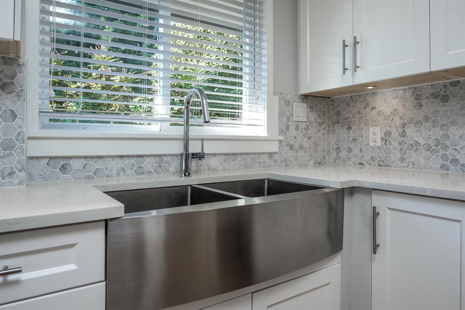 The apron sink under the window, marble carried up the wall.
