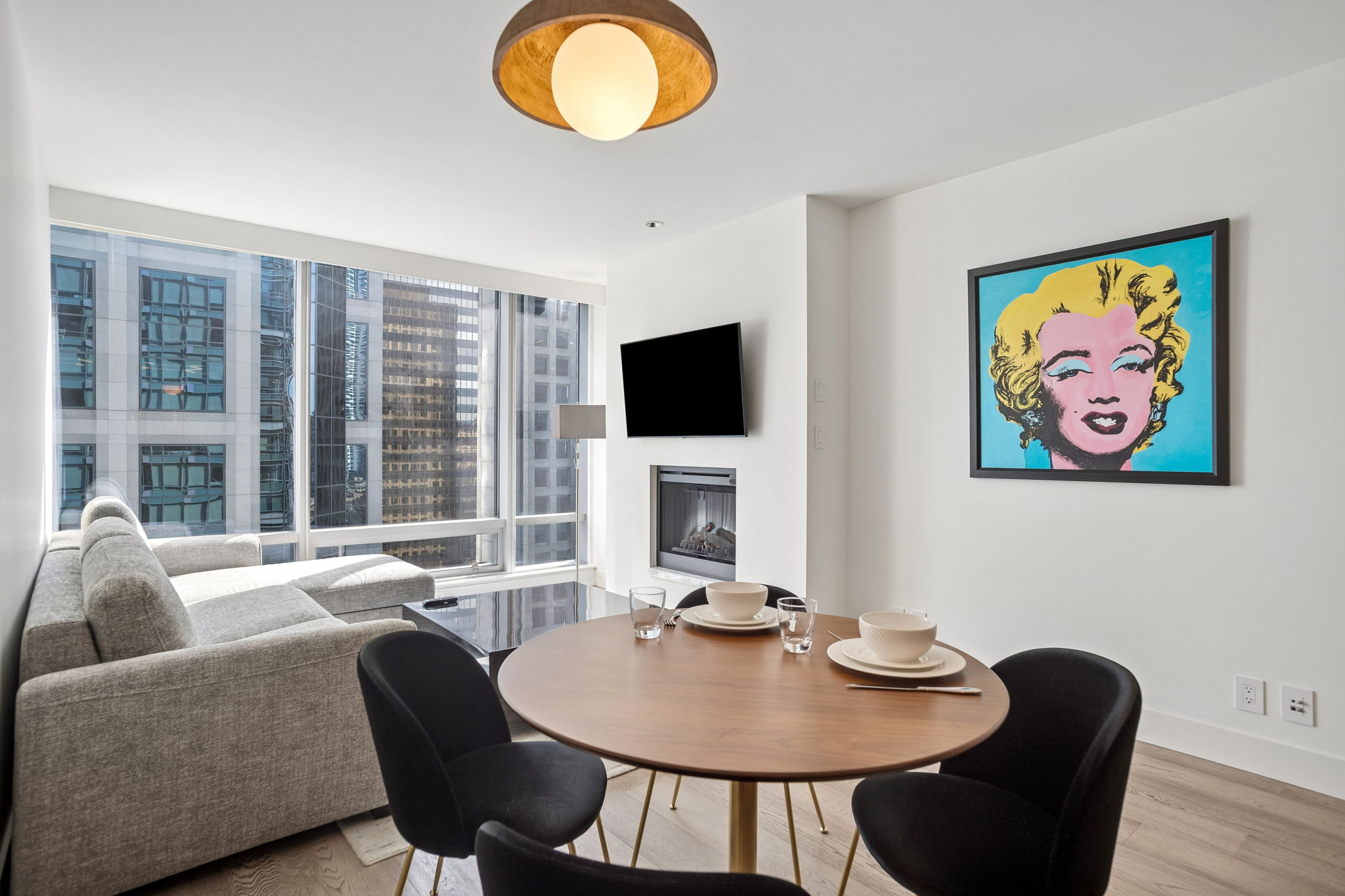 The living and dining room, with the fireplace, a wall-mounted television and a framed Marilyn Monroe print.