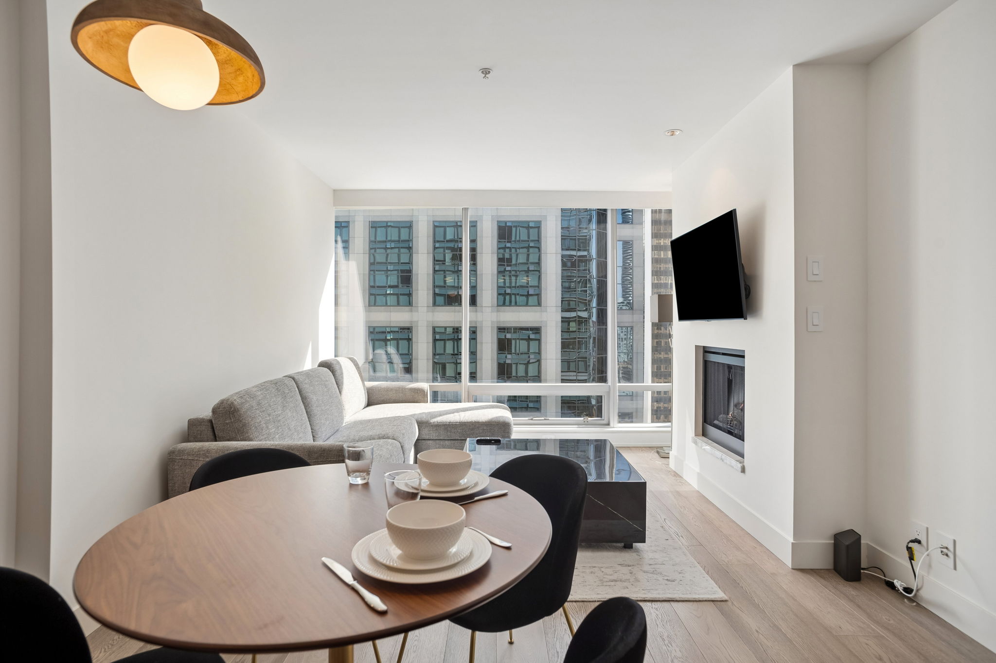 The dining table by the windows, with the sofa and the fireplace beyond.