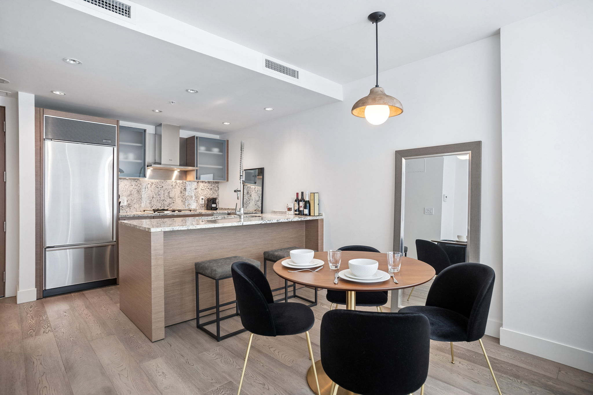 The kitchen island with bar stools, seen across the dining table.