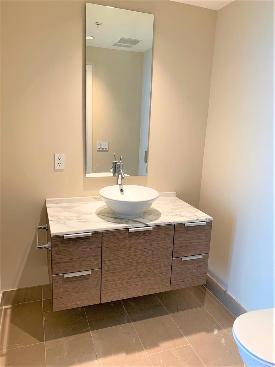 The bathroom vanity, a vessel basin on a marble top with a mirror running up the wall.