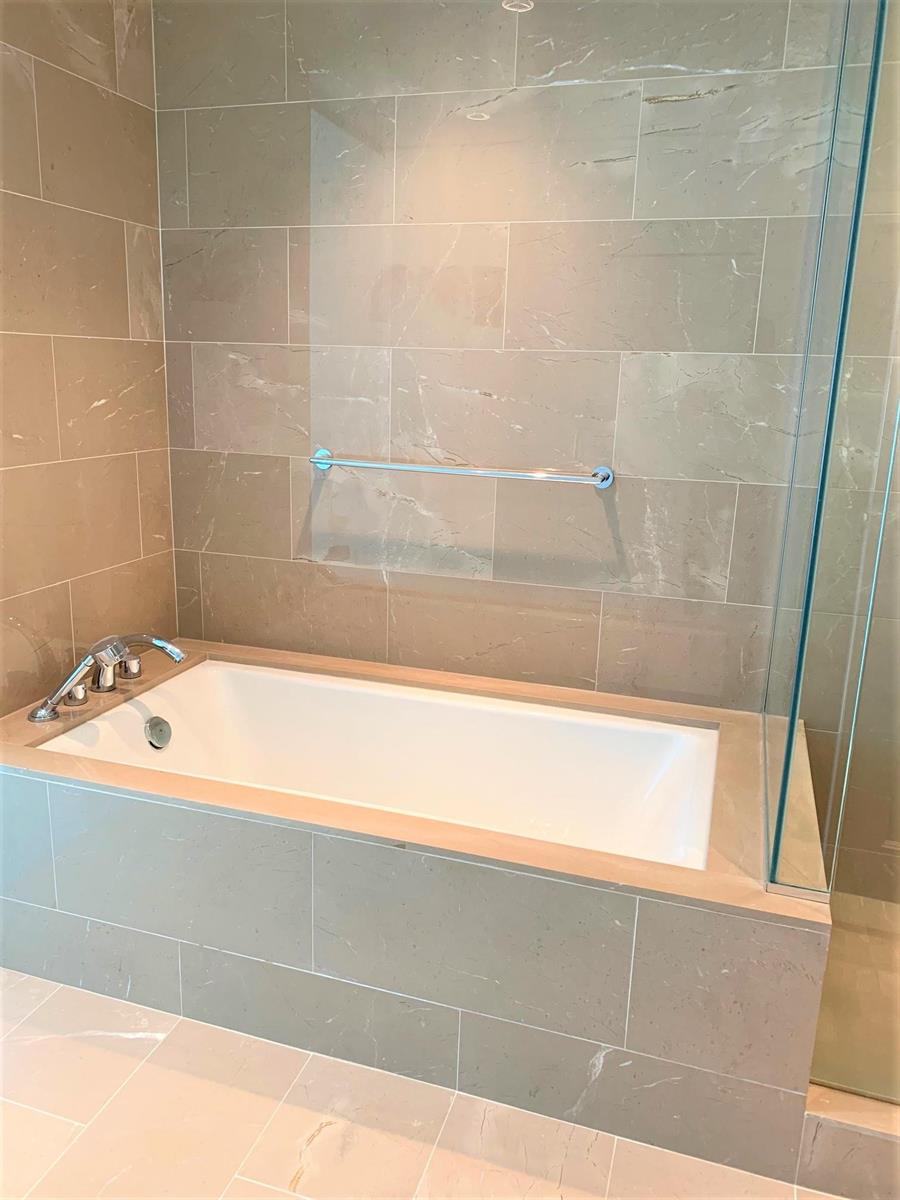 The soaker tub set along the stone wall, the shower glass to the right.