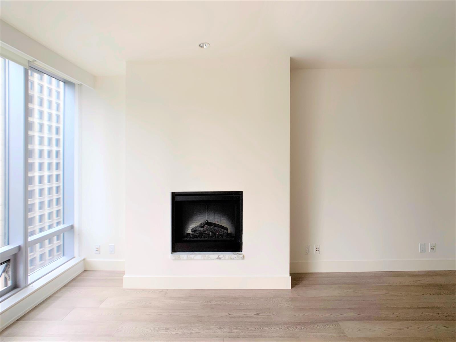 The fireplace between the windows and the dining end, the room empty and bright.