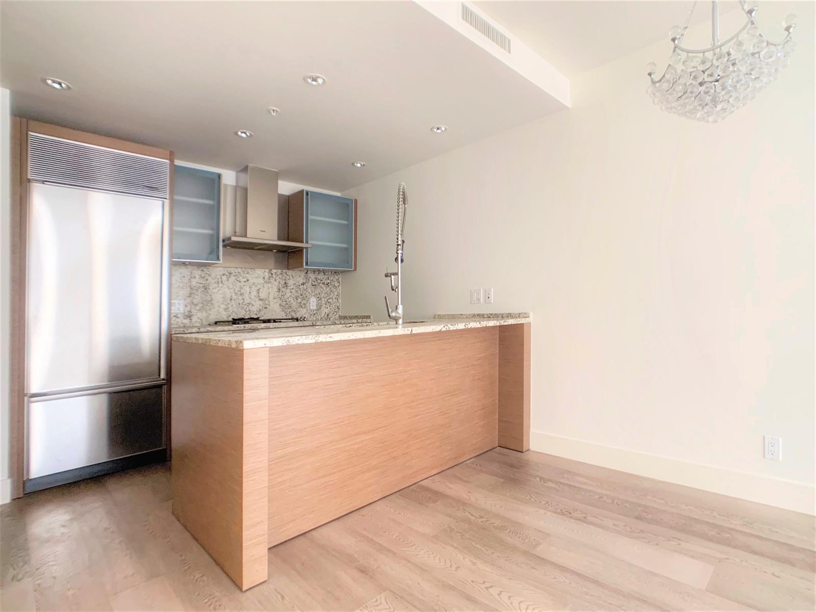 The kitchen island end on, the integrated refrigerator and cabinets along the far wall.