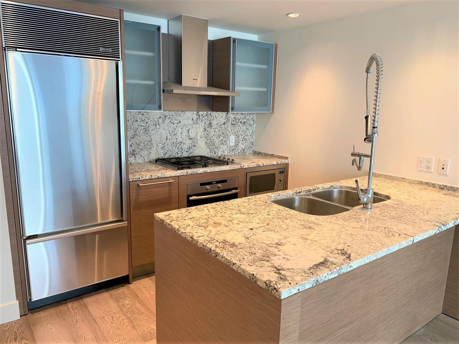 The kitchen, a gas cooktop under a stainless hood with the sink set into the island.