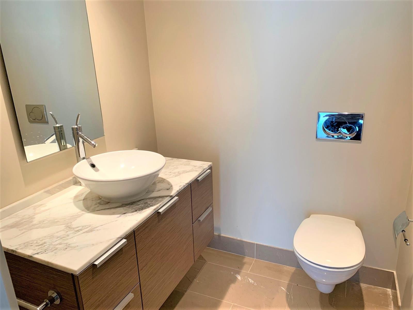 The washroom by the entry, a vessel basin on a timber vanity with a tall mirror above.
