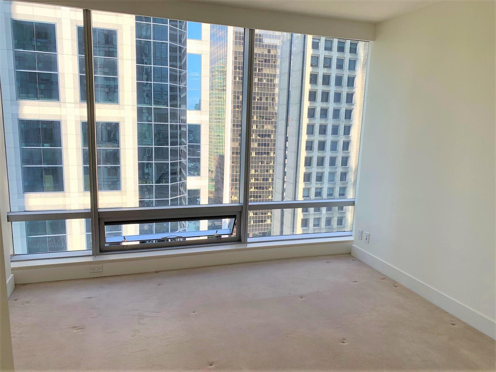 The bedroom, full-height windows filling the wall with the neighbouring towers close outside.