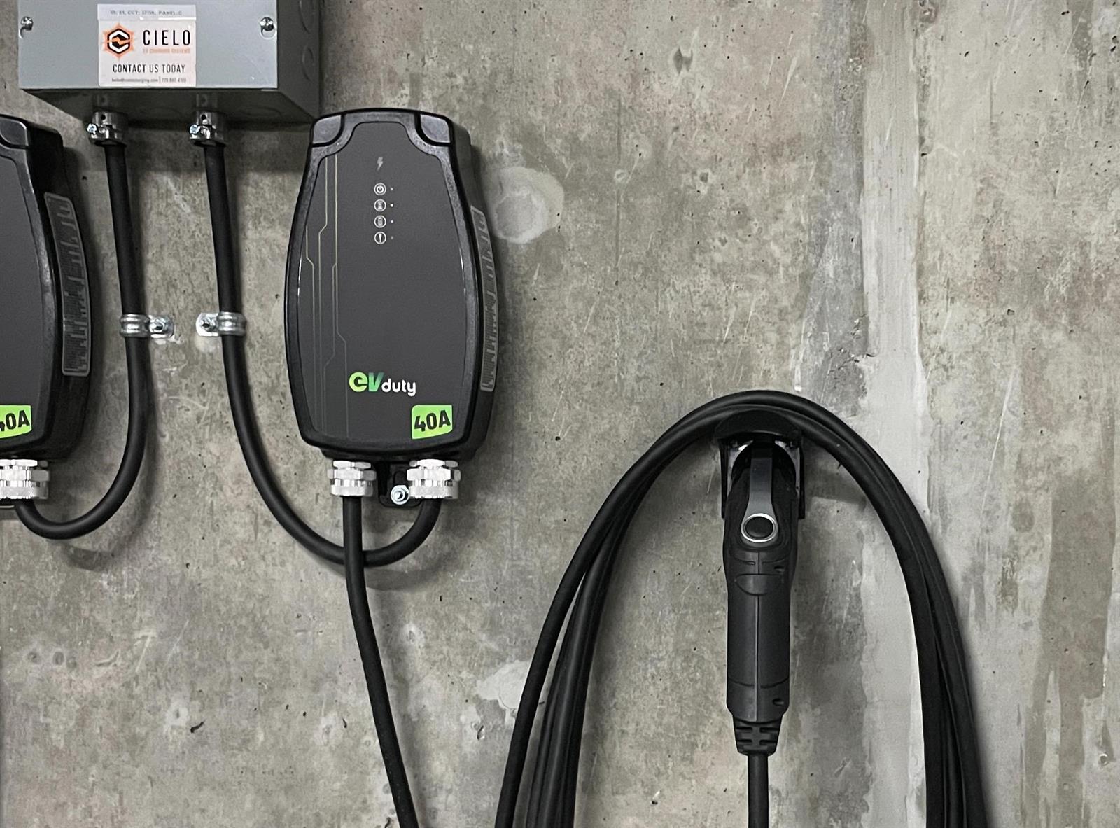 The parking stall's own EV charging point, mounted on the concrete wall with its cable coiled beside it.