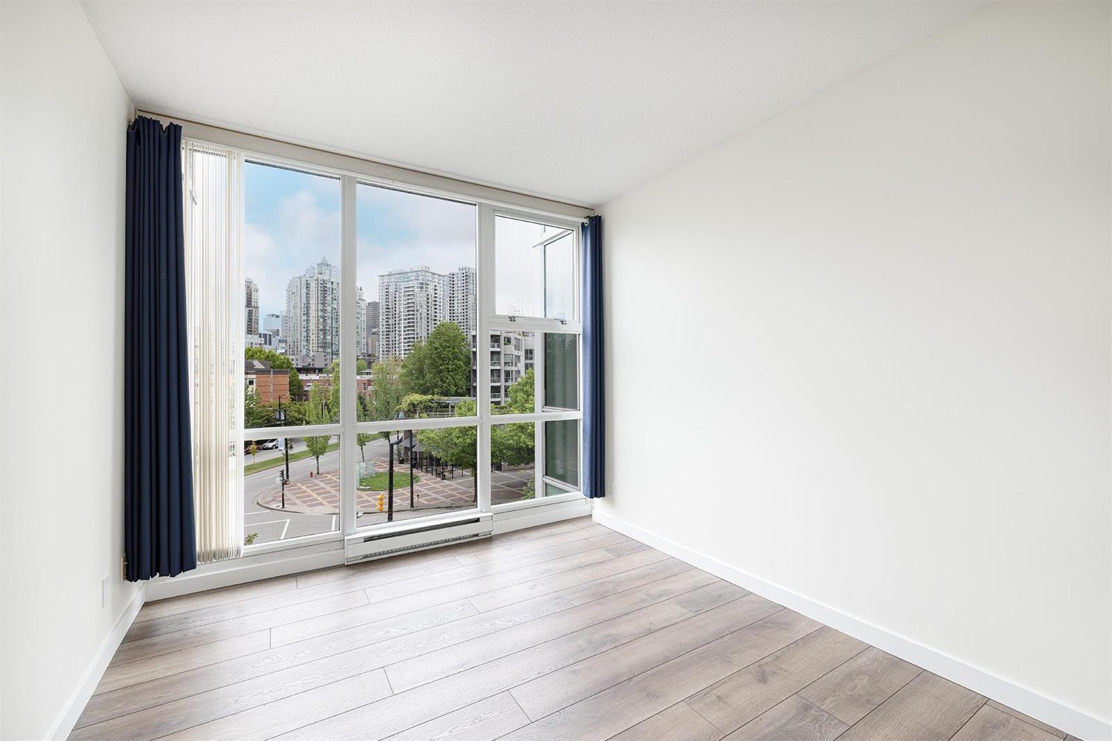 The bedroom, with a full-height window and navy curtains looking over the park and the towers past it.