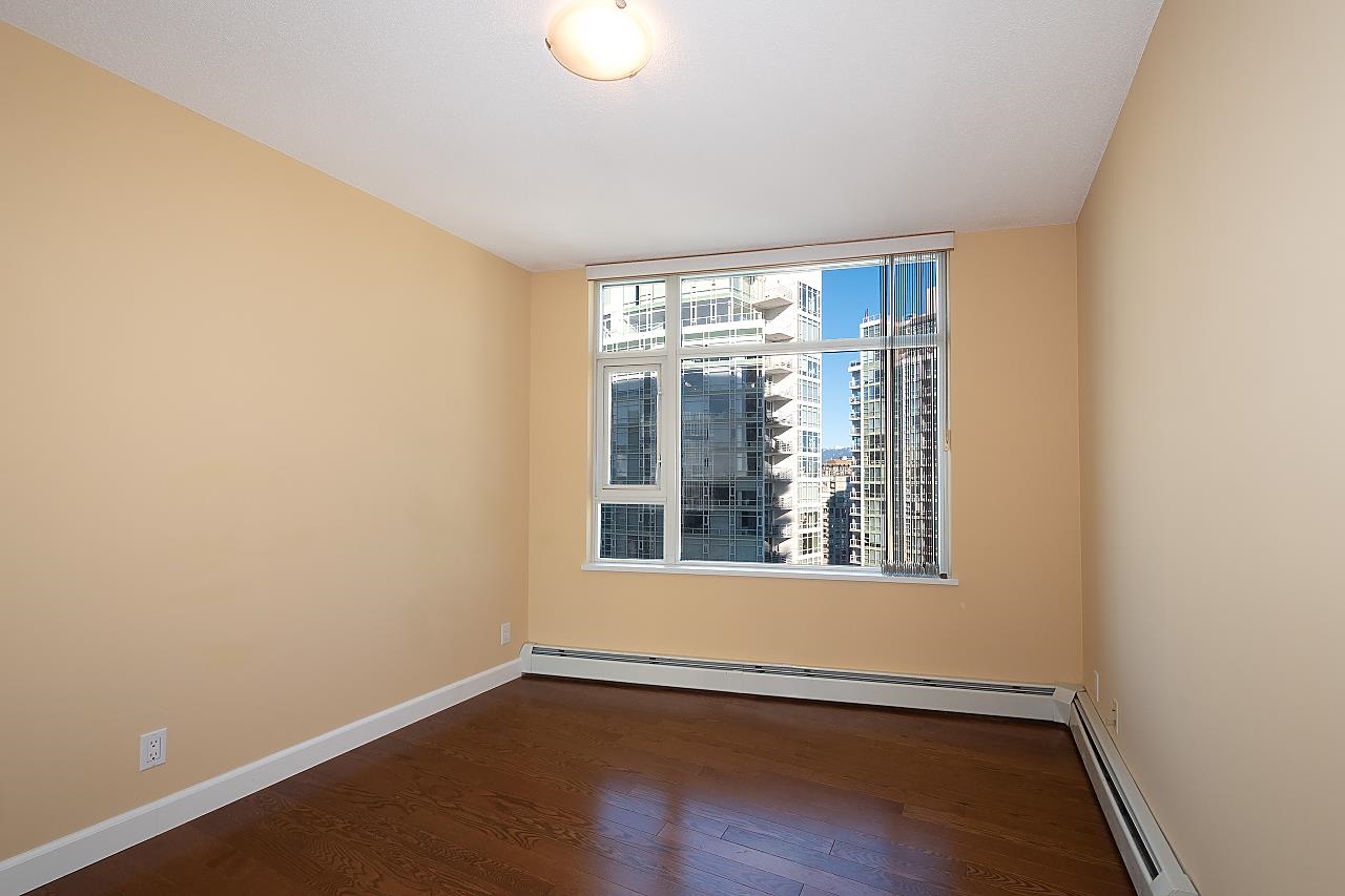 A bedroom, empty, a tall window looking across to the neighbouring towers.