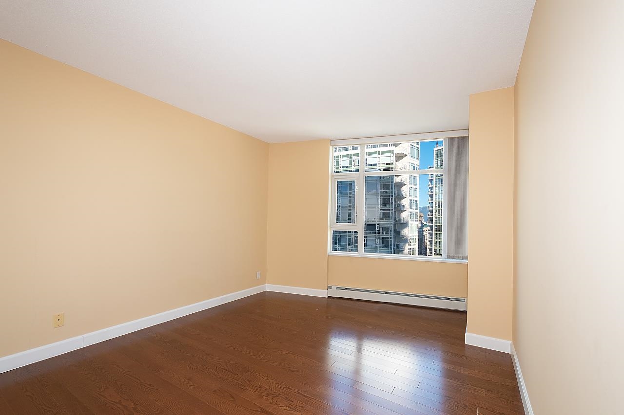 The second bedroom, hardwood underfoot and a window on the far wall.