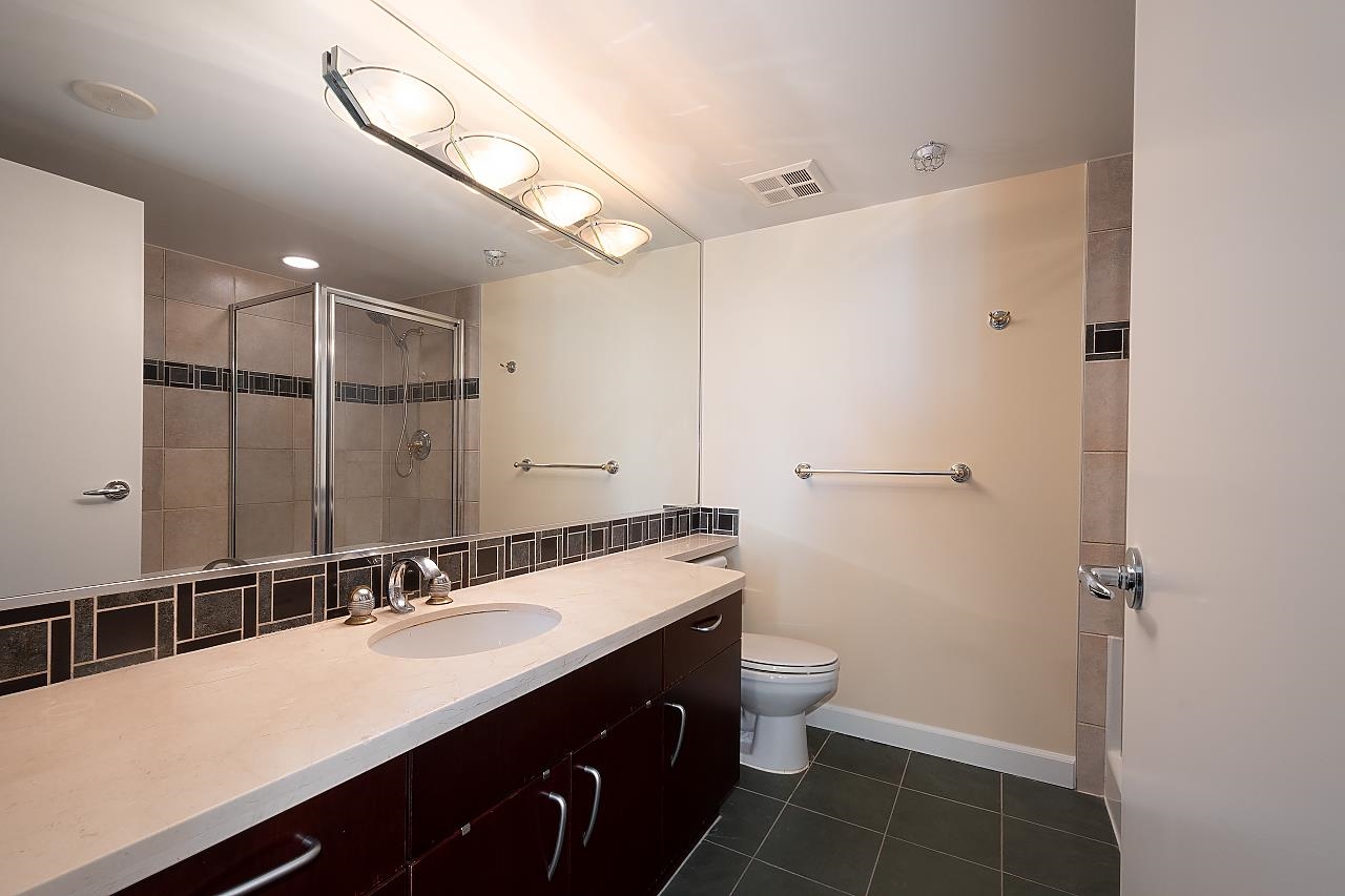 The other bathroom, a long vanity under a full-width mirror with the shower glazed beside it.