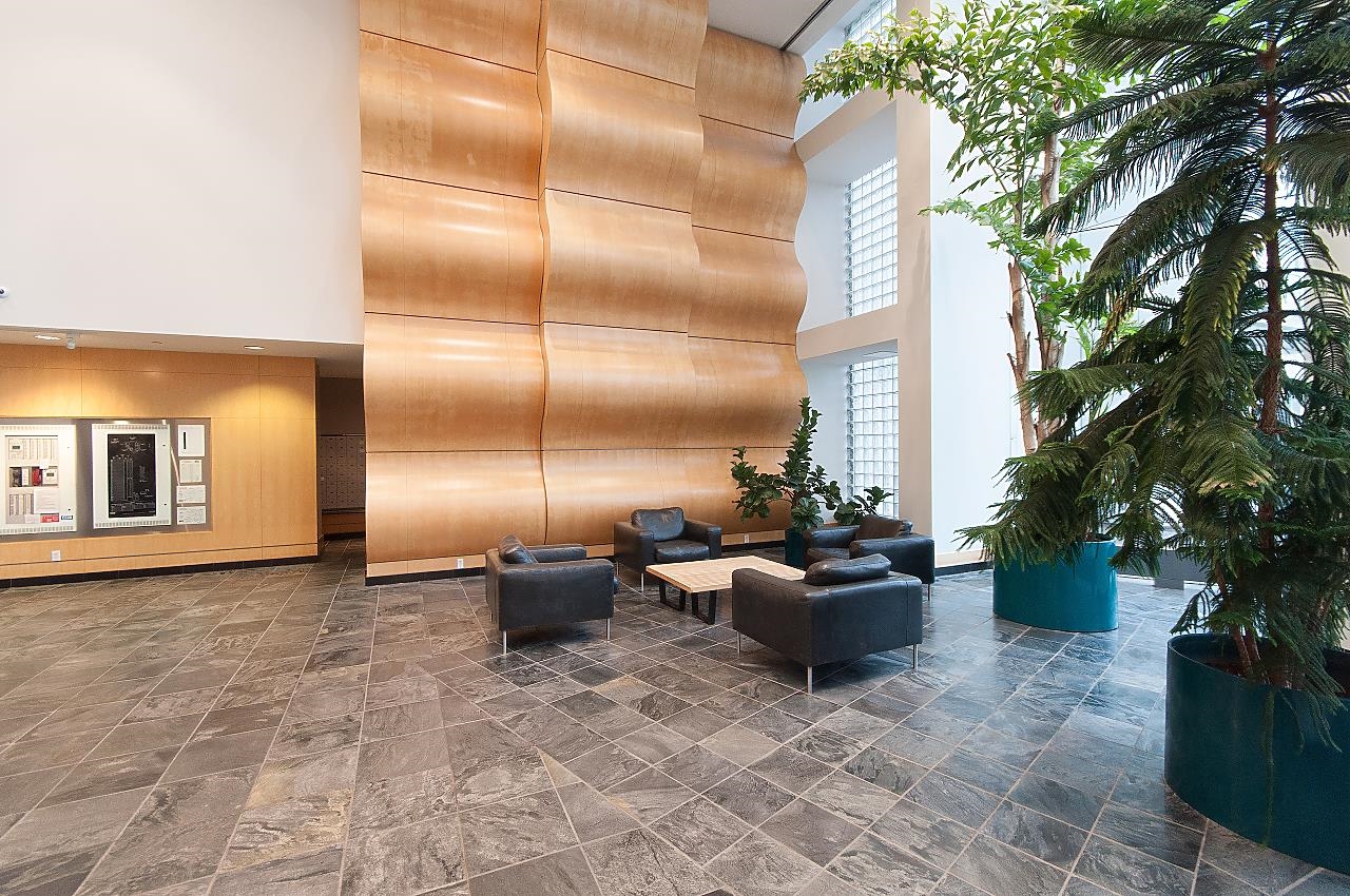 The building's lobby, a curved timber wall rising two storeys above a slate floor and leather chairs.