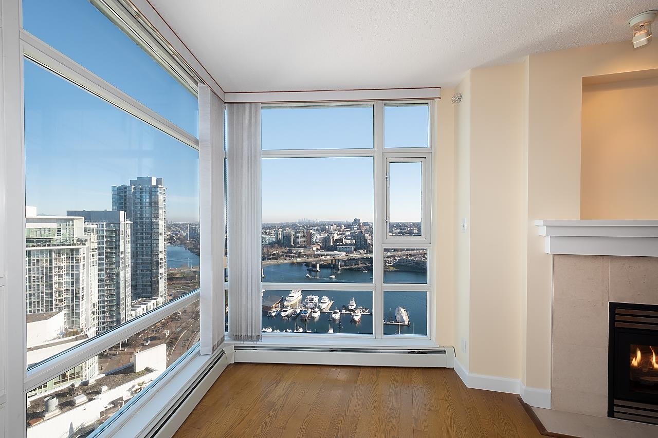 The corner of the living room in glass, the marina below the sill and the skyline along the horizon.