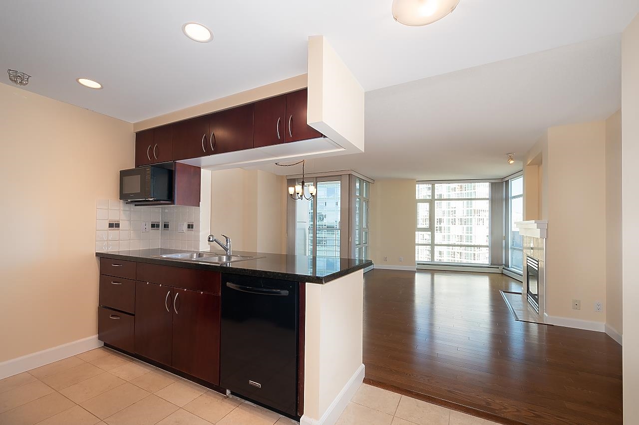 The kitchen seen over its granite counter, cherry cabinets and the living room windows beyond.