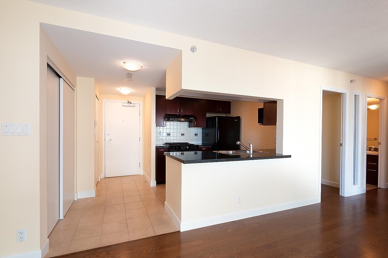 The entry hall in tile, with the kitchen open to the right and the living room floor beyond.