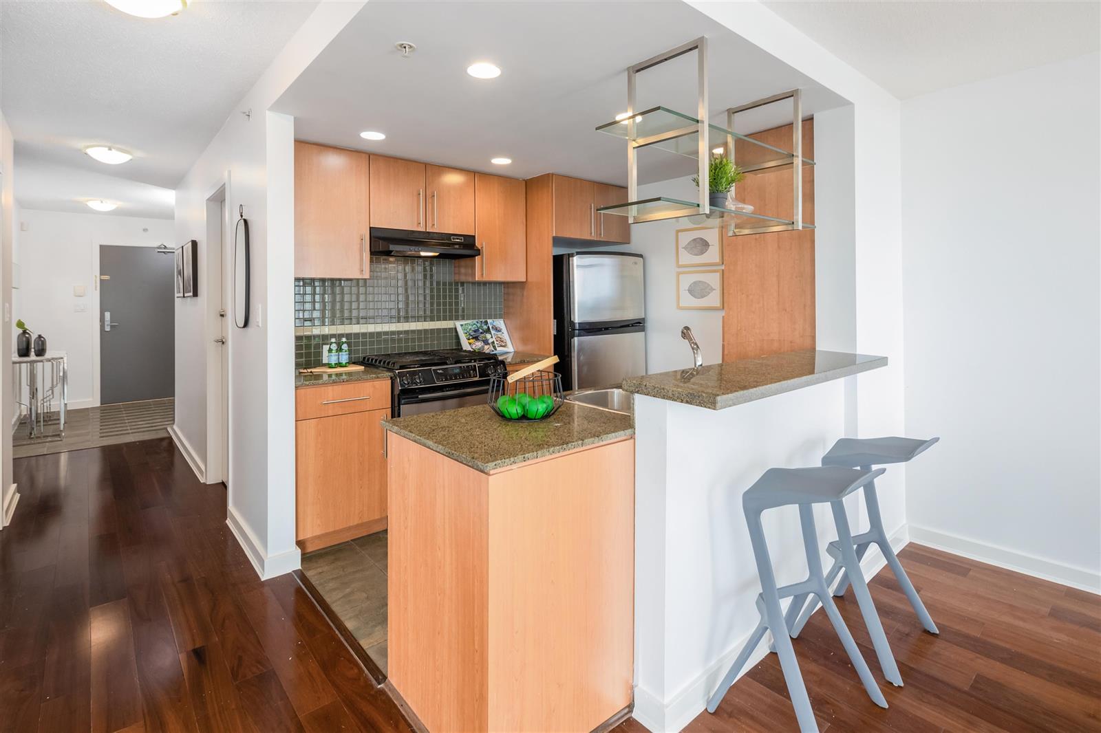 The kitchen from the hall, an island with two stools and the range against the far wall.