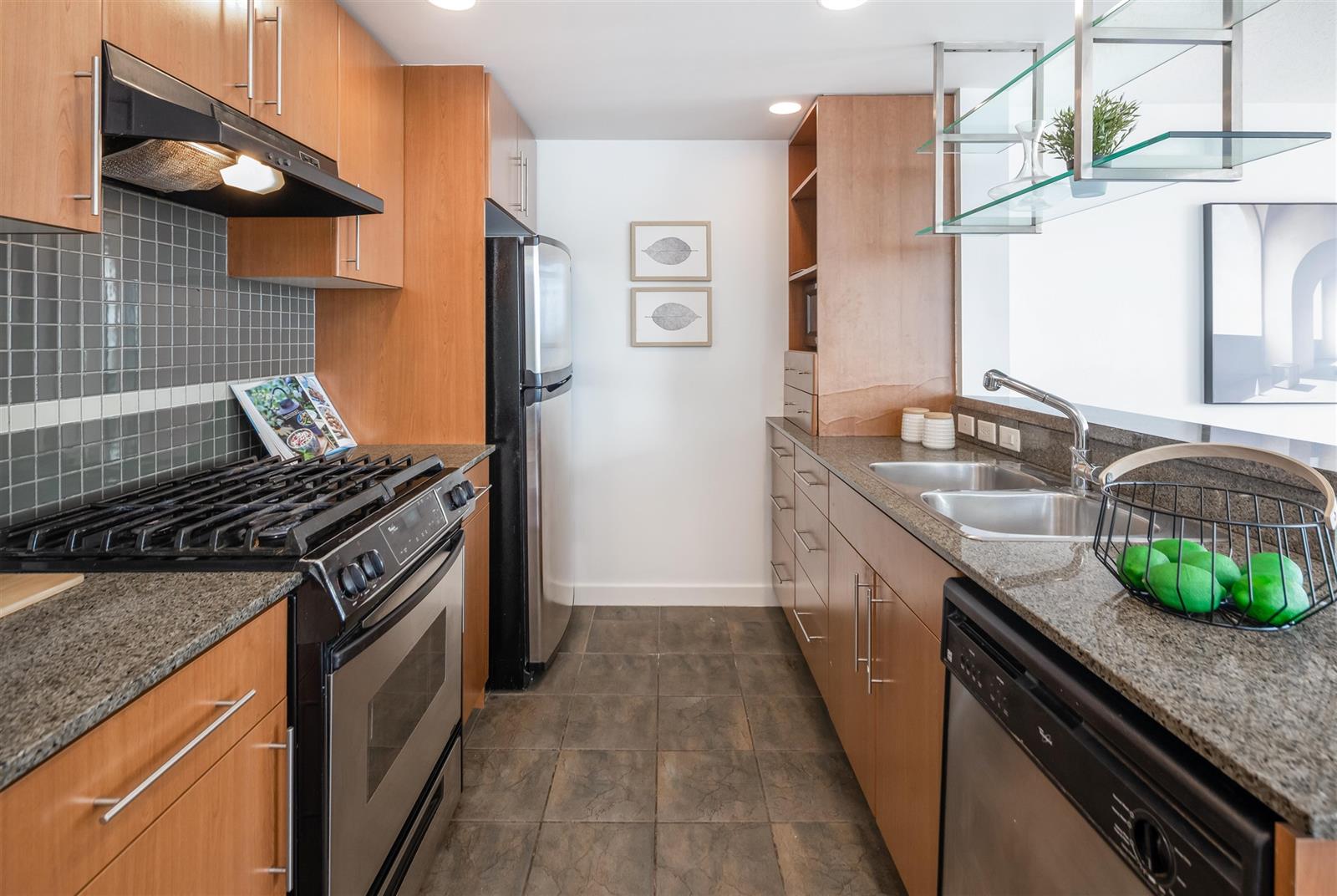 The kitchen, a gas range under a stainless hood with granite counters either side.