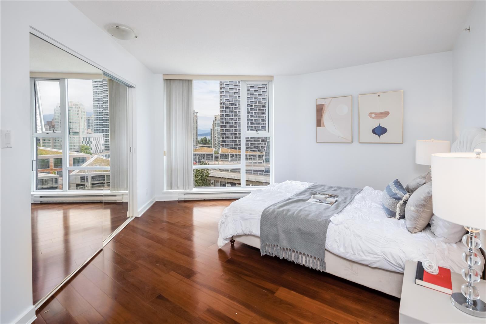 A bedroom, the bed against the wall with the window running the length of the room.