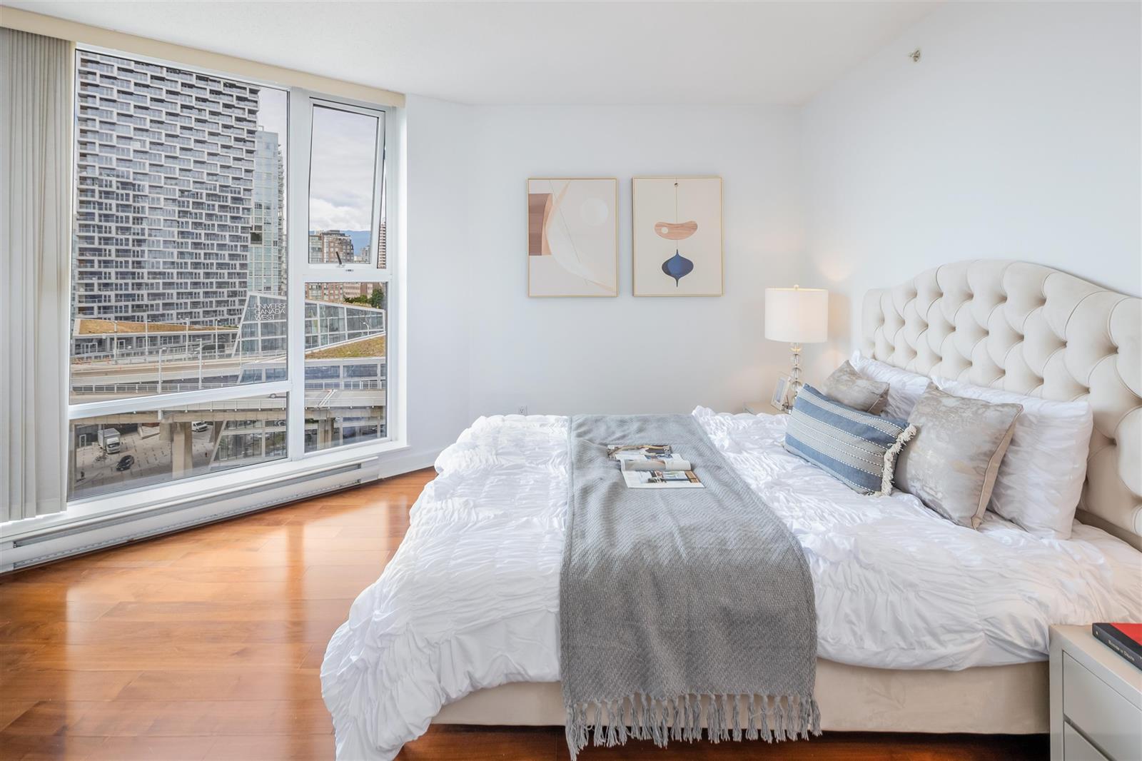 The primary bedroom, a tufted headboard against the wall and the window wall to the left.