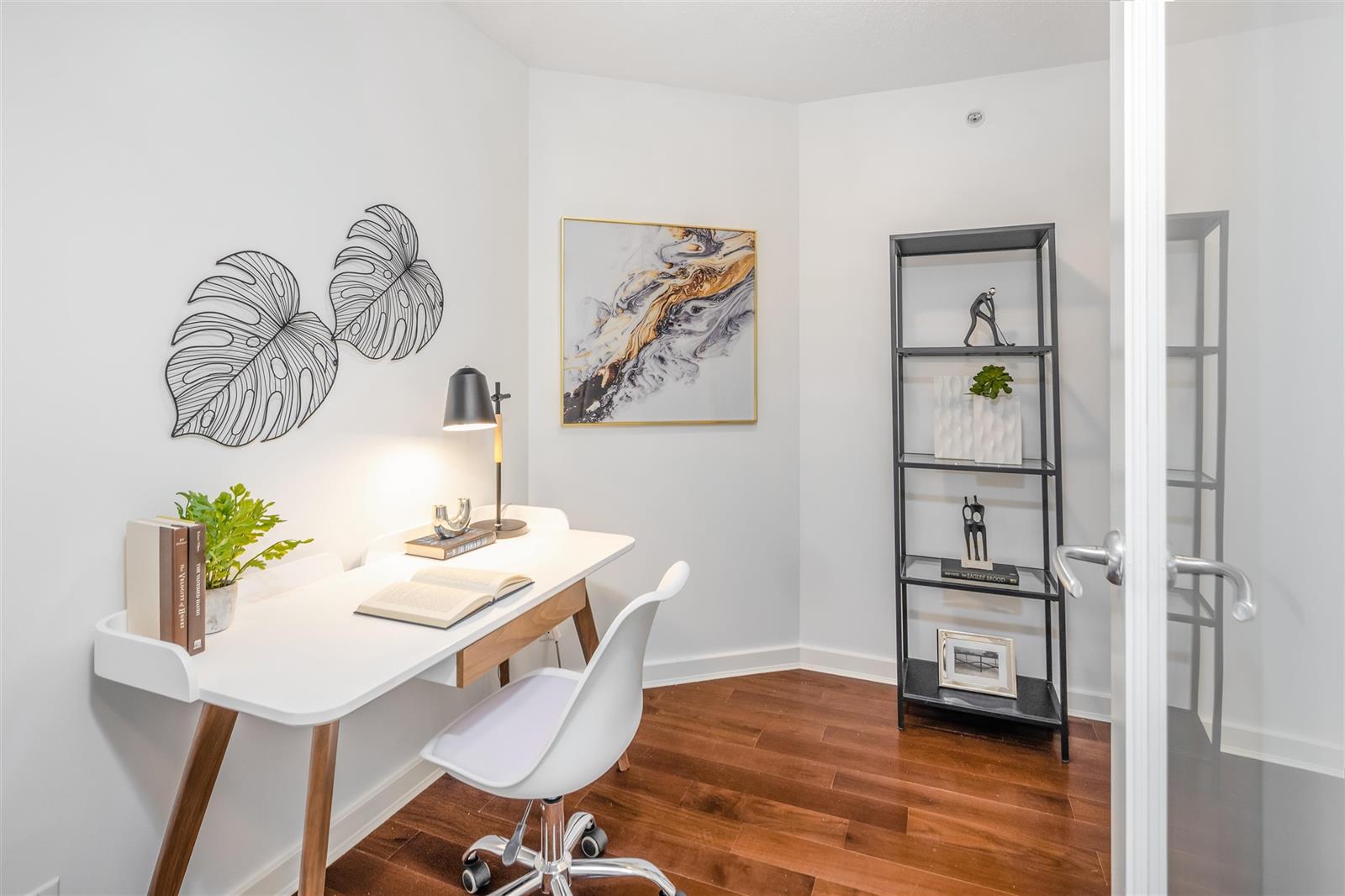 The den off the hall, a desk under a shelf unit with a door to the side.