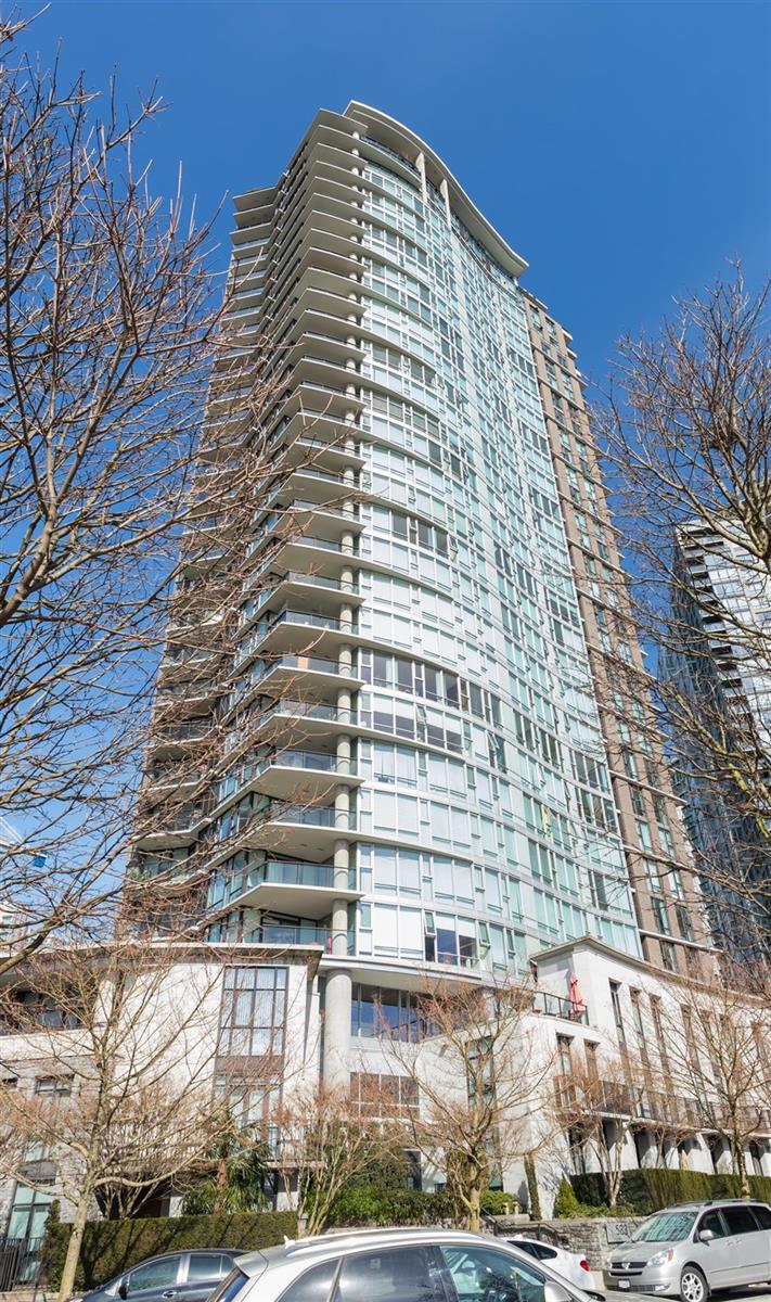 The tower from Beach Crescent, curved glass rising against a clear sky.