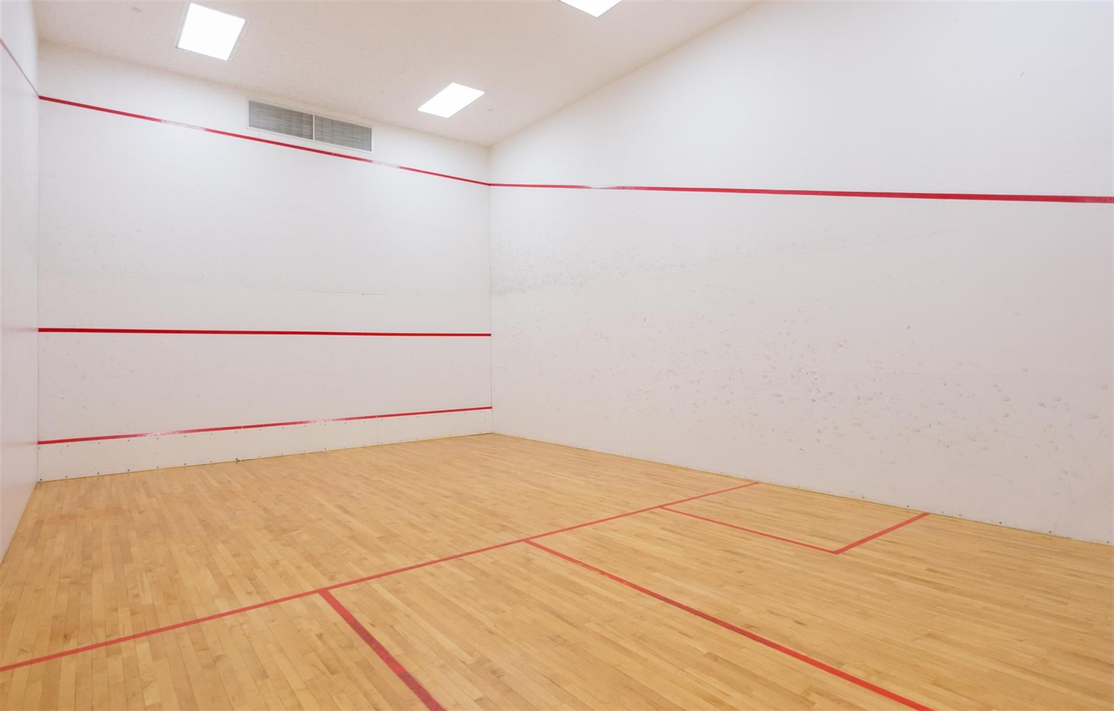 The squash court, white walls with the service lines marked in red.