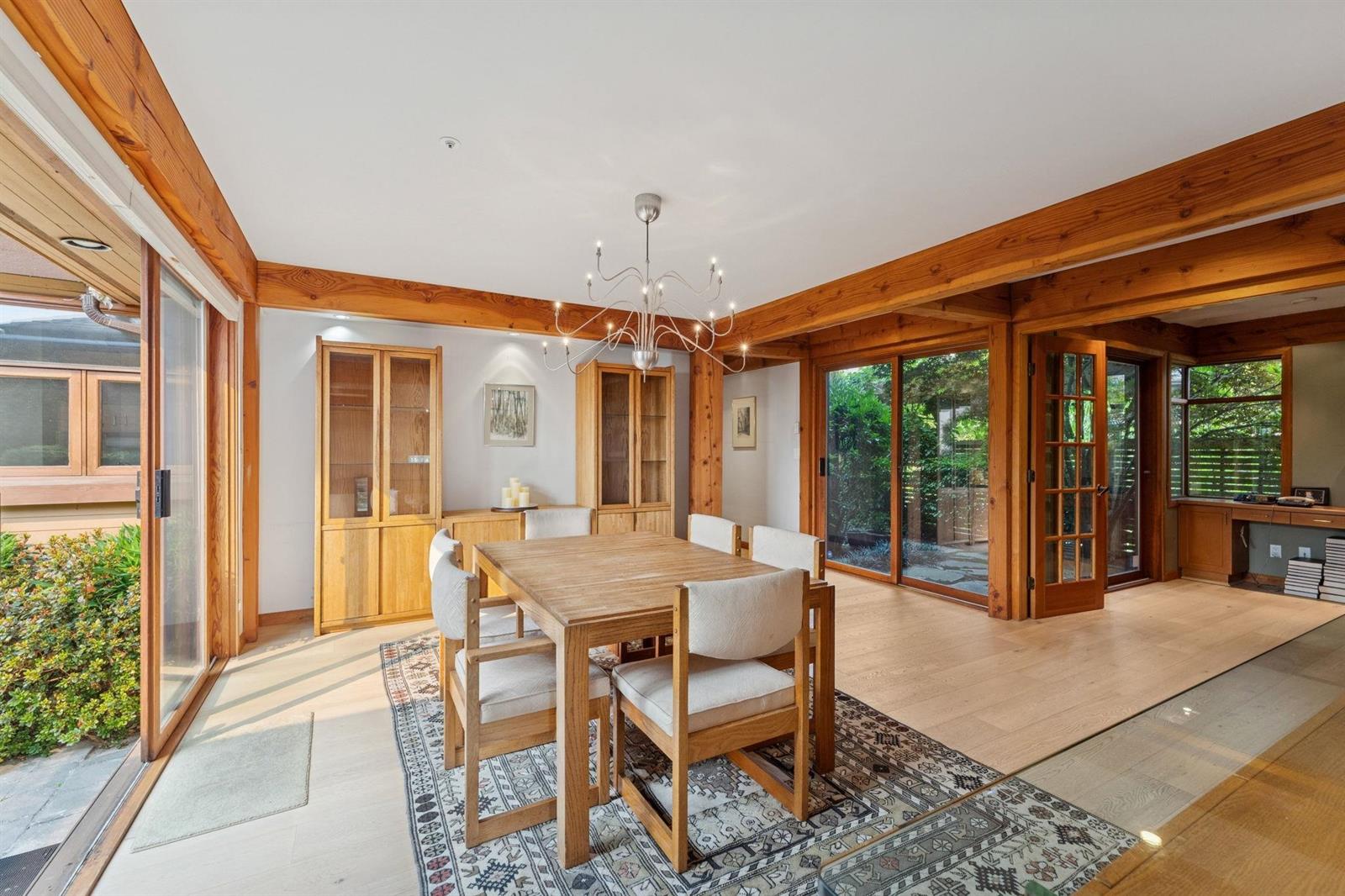 The dining table seen from the kitchen doorway, chairs on a patterned rug.