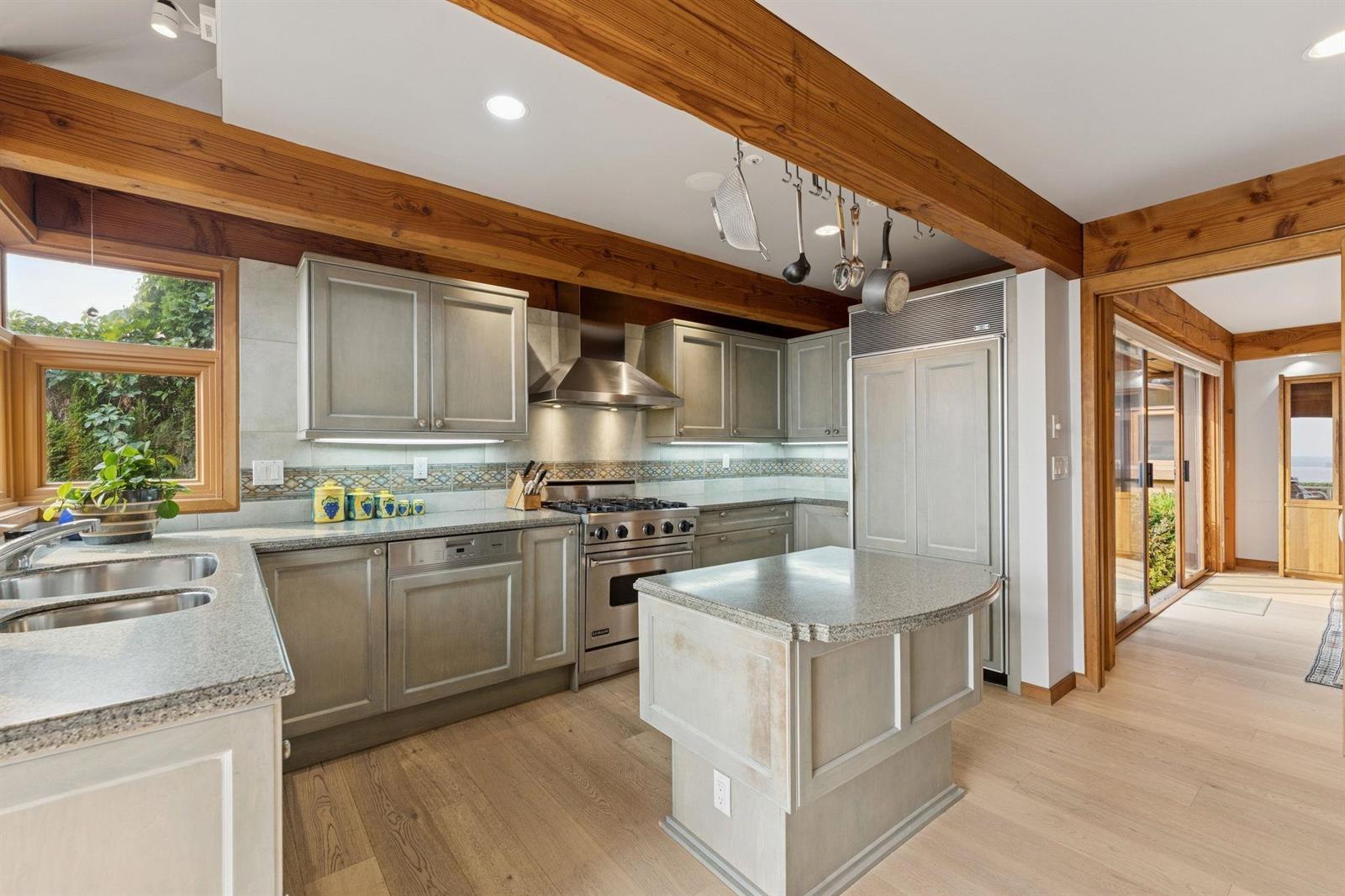The kitchen from the dining side, stainless counters under exposed beams.