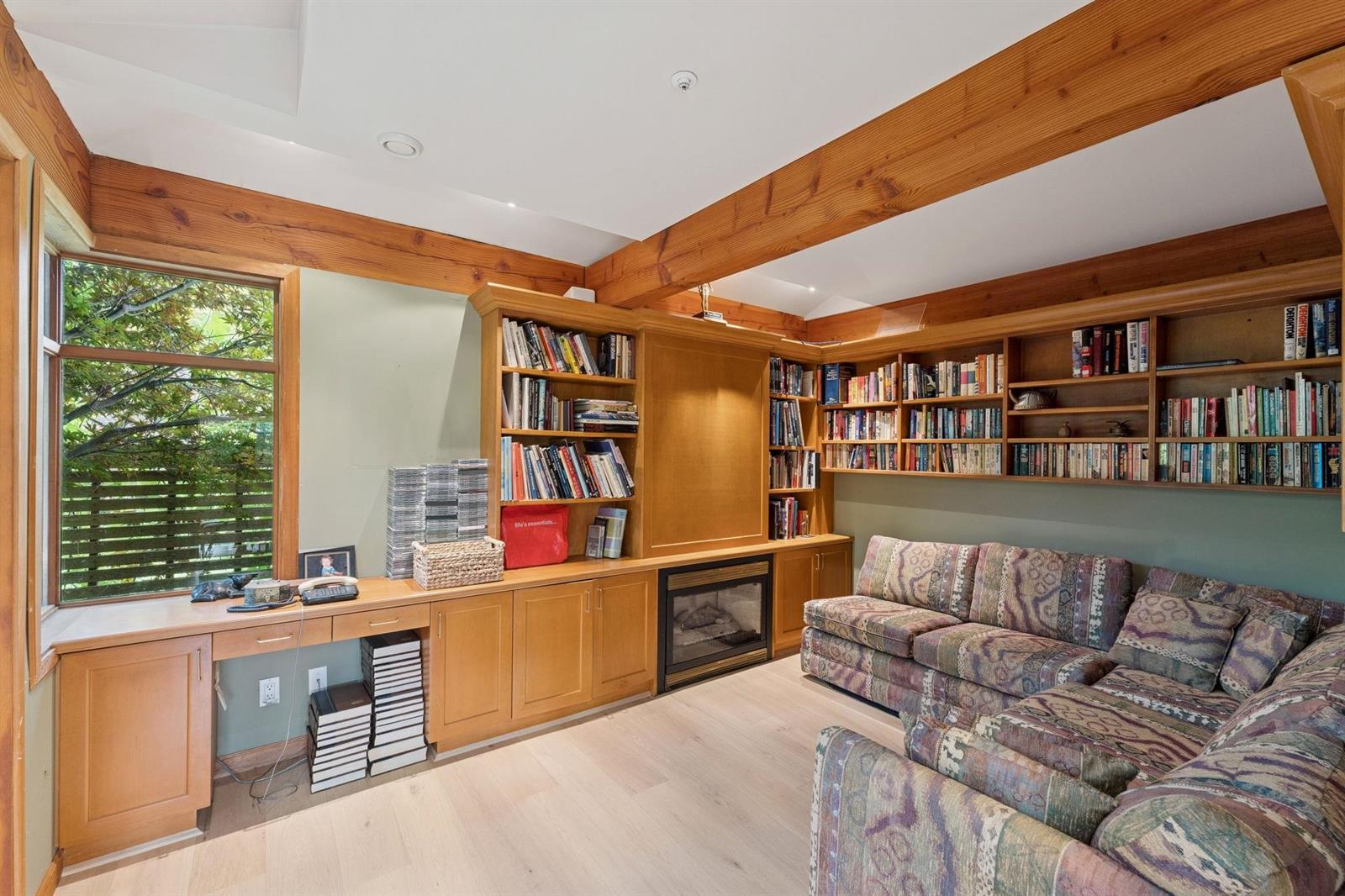 The library, books floor to ceiling on two walls with a sofa beneath the window.