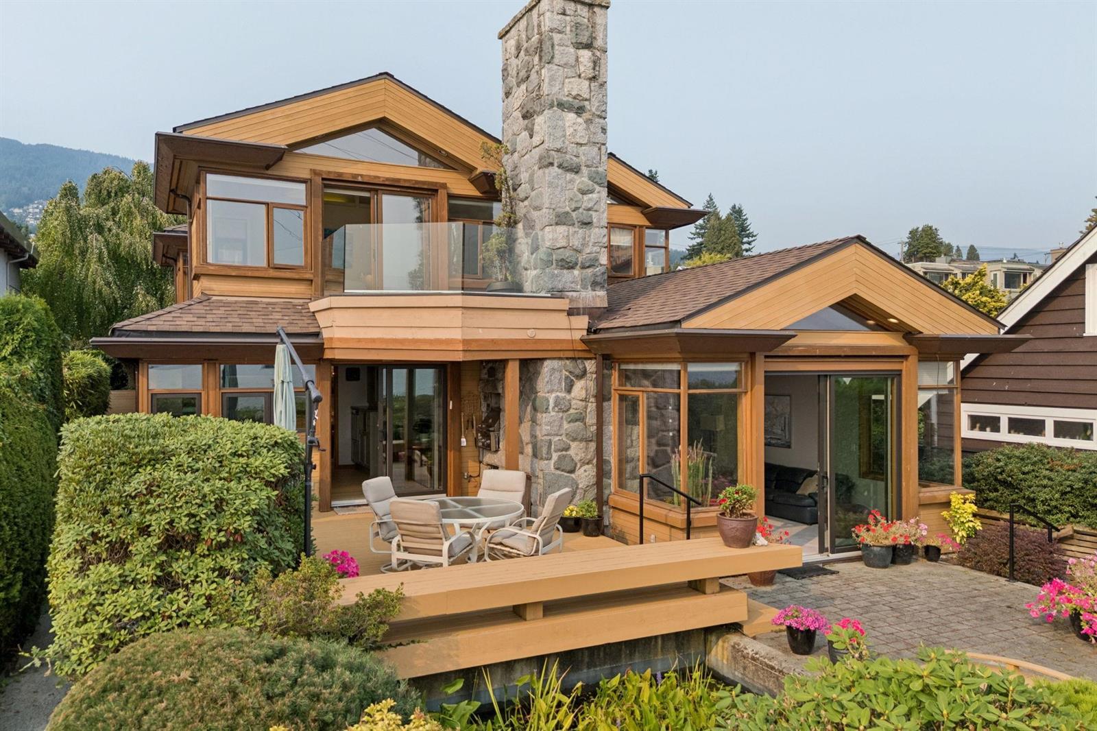 The house from the side, the deck and its timber rail wrapping around toward the water.