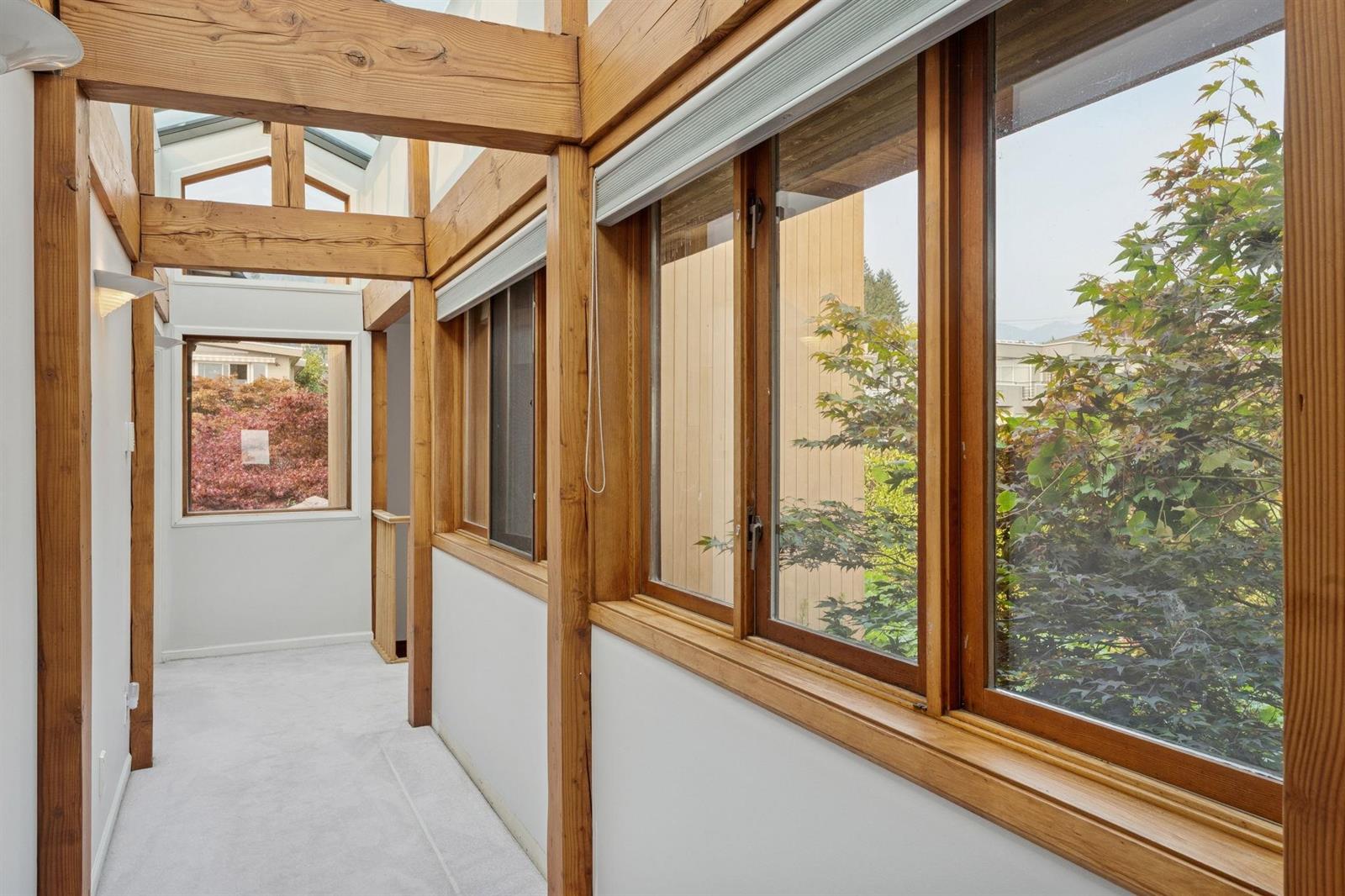 A glazed hallway between the rooms, windows on both sides looking into the garden.