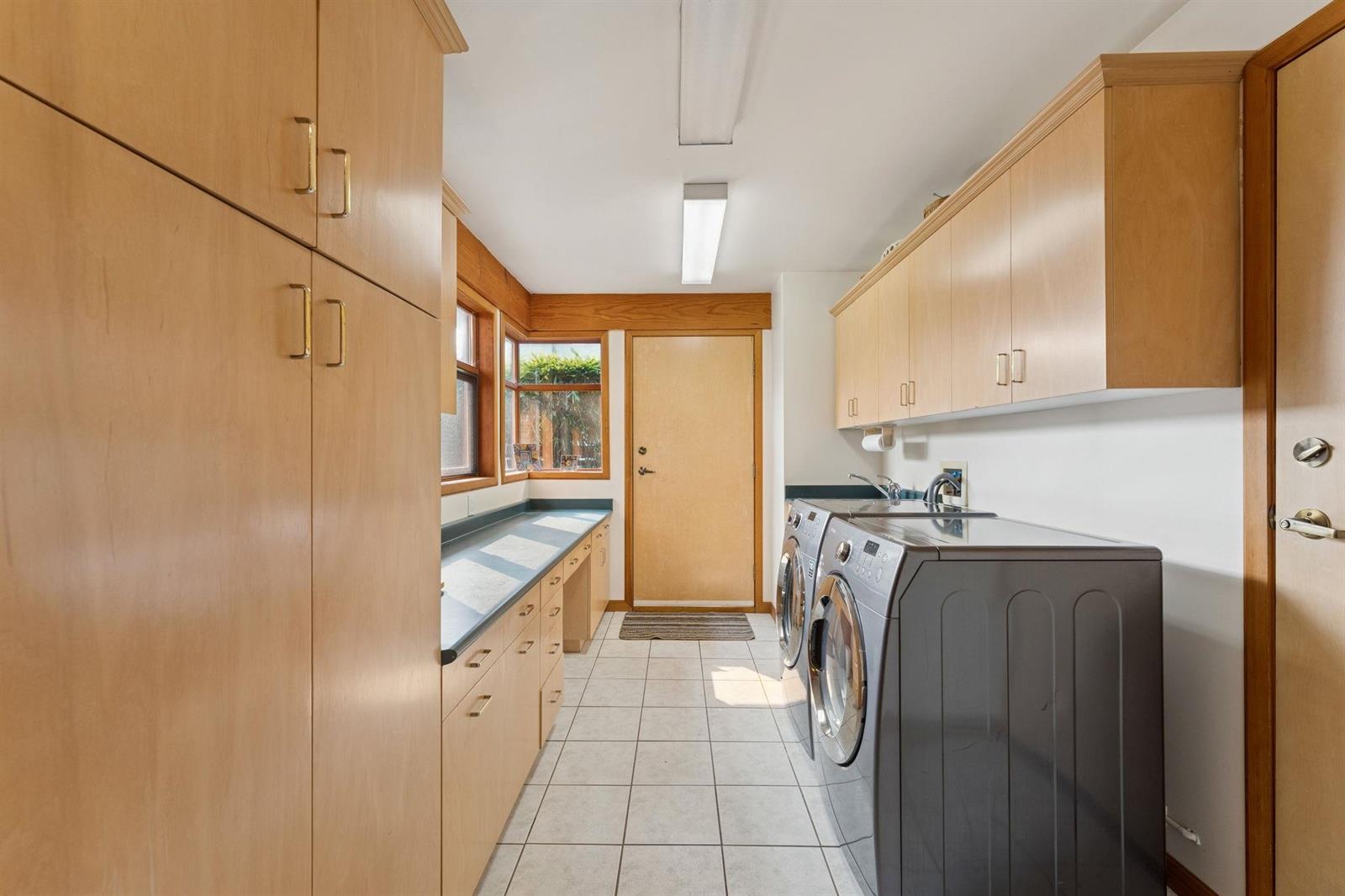 The laundry room, washer and dryer beneath wood cabinets.