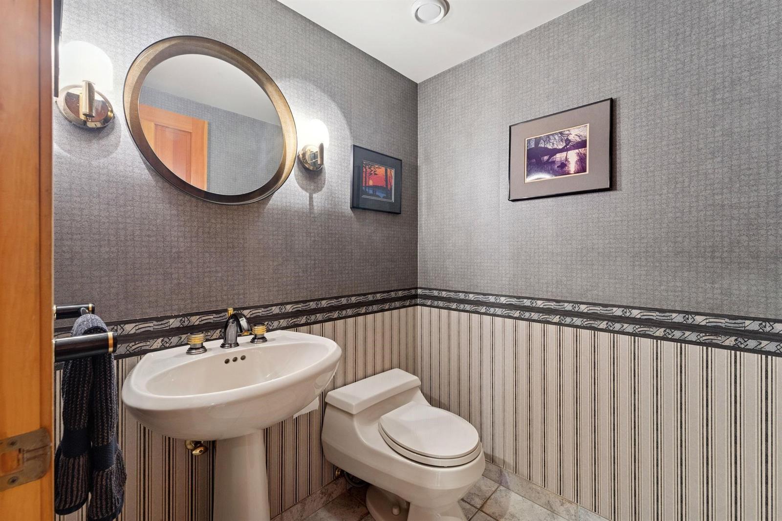 The powder room, a pedestal basin under a round mirror.