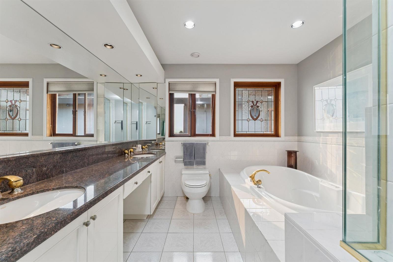 The ensuite bathroom, a stone counter and a soaking tub beside the glass shower.