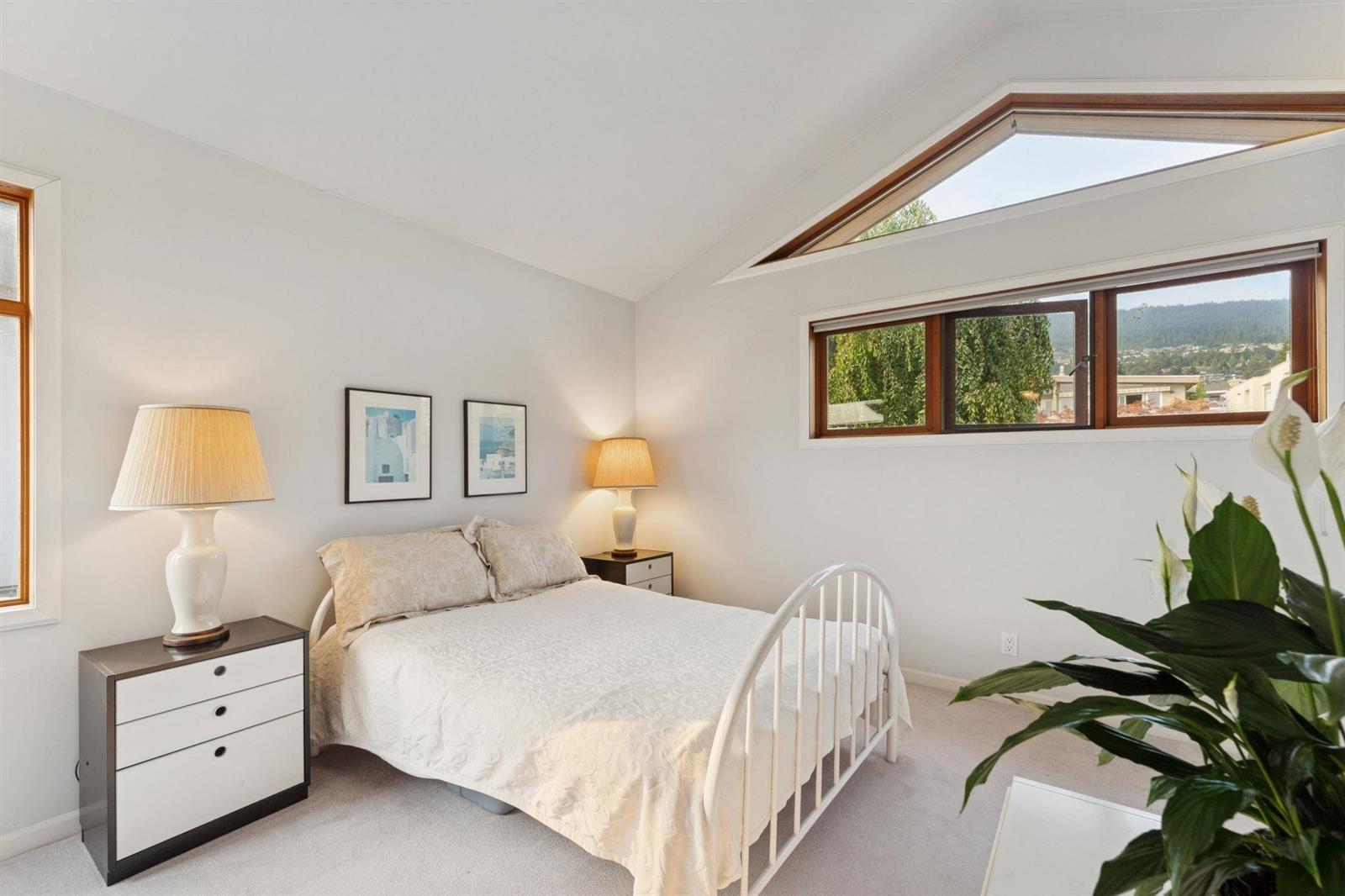 The same bedroom from the other side, a skylight above and a plant by the window.