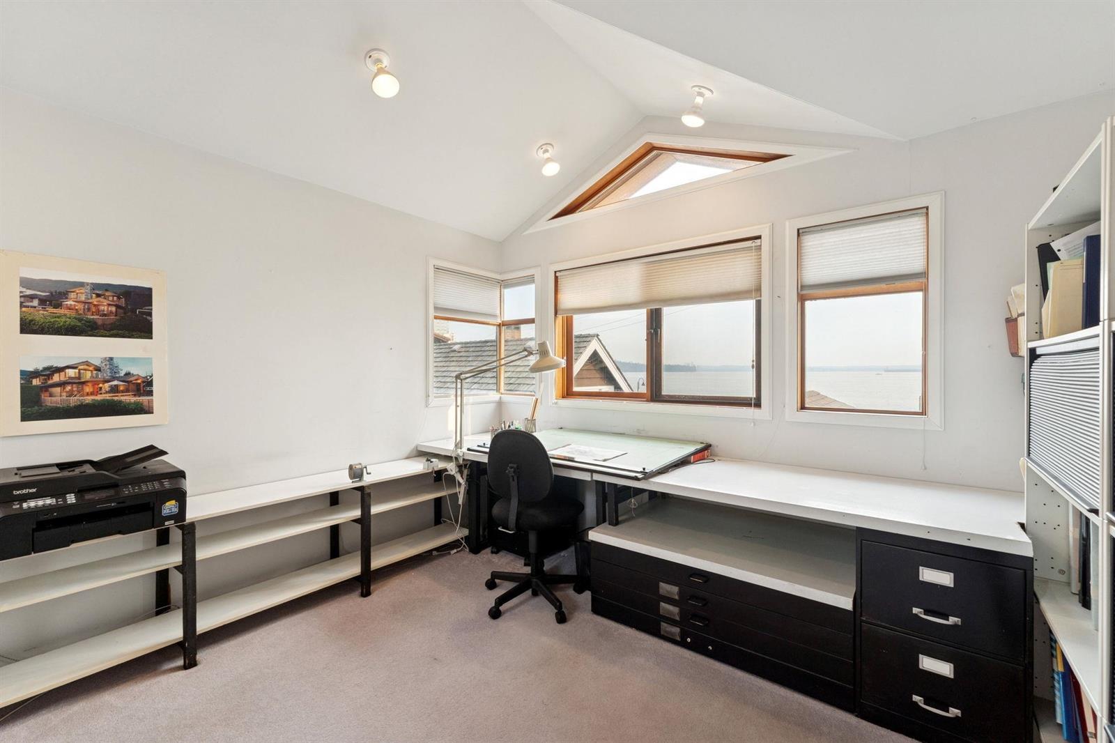 The office, a drafting table and filing cabinets beneath a sloped ceiling.