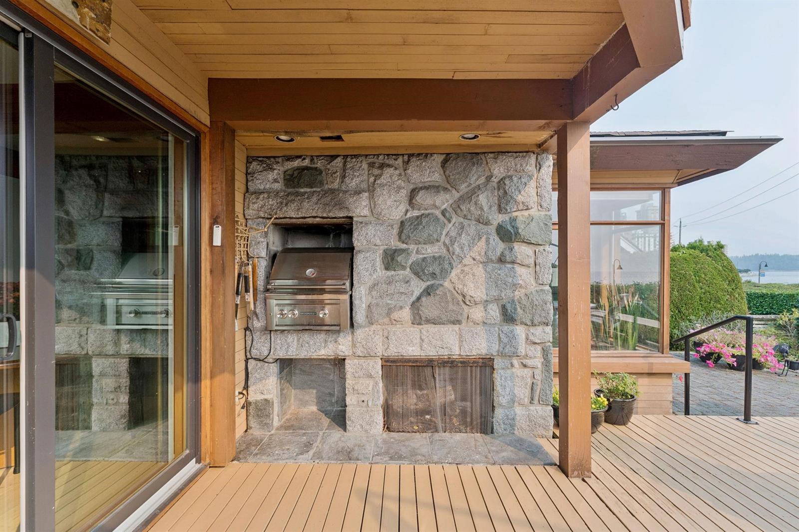 The covered terrace with its own stone fireplace, looking out through timber posts.