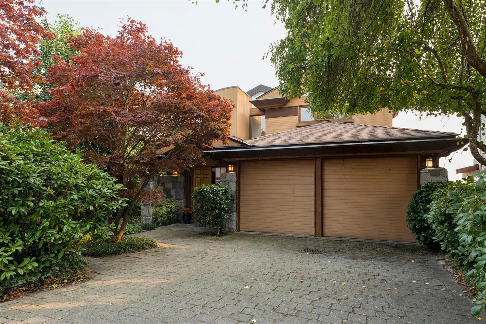 The garage doors at the end of the gravel drive, maples overhanging.