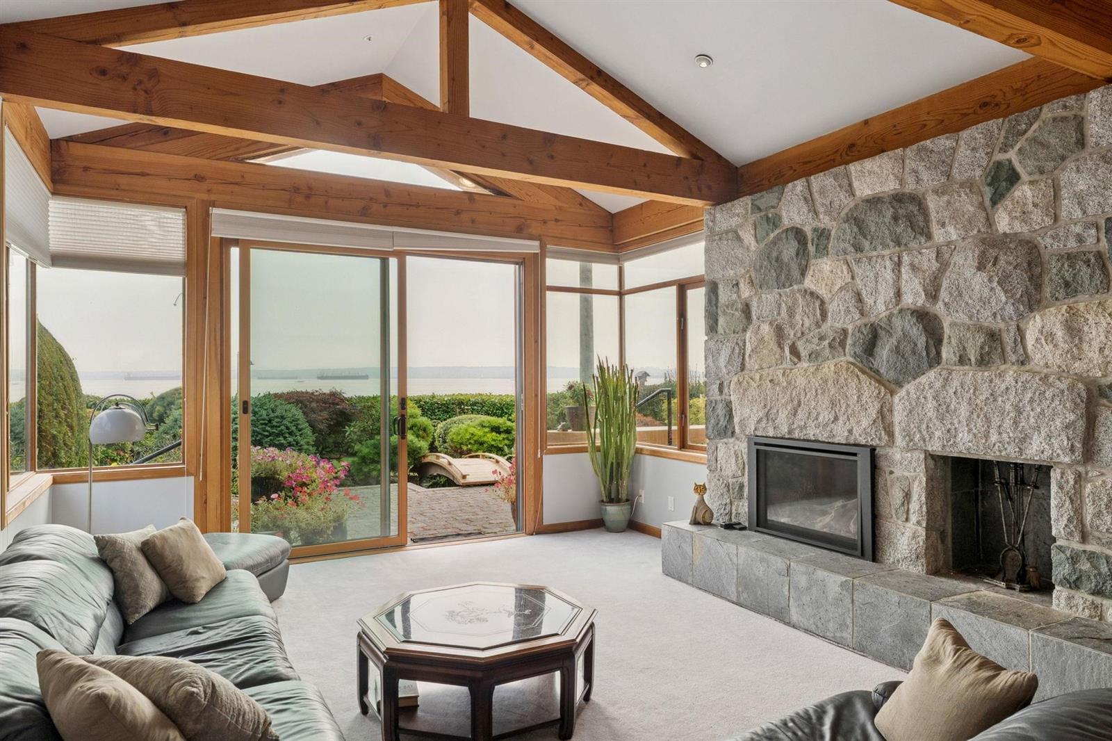 The living room, a stone fireplace between two walls of glass looking out to the ocean.