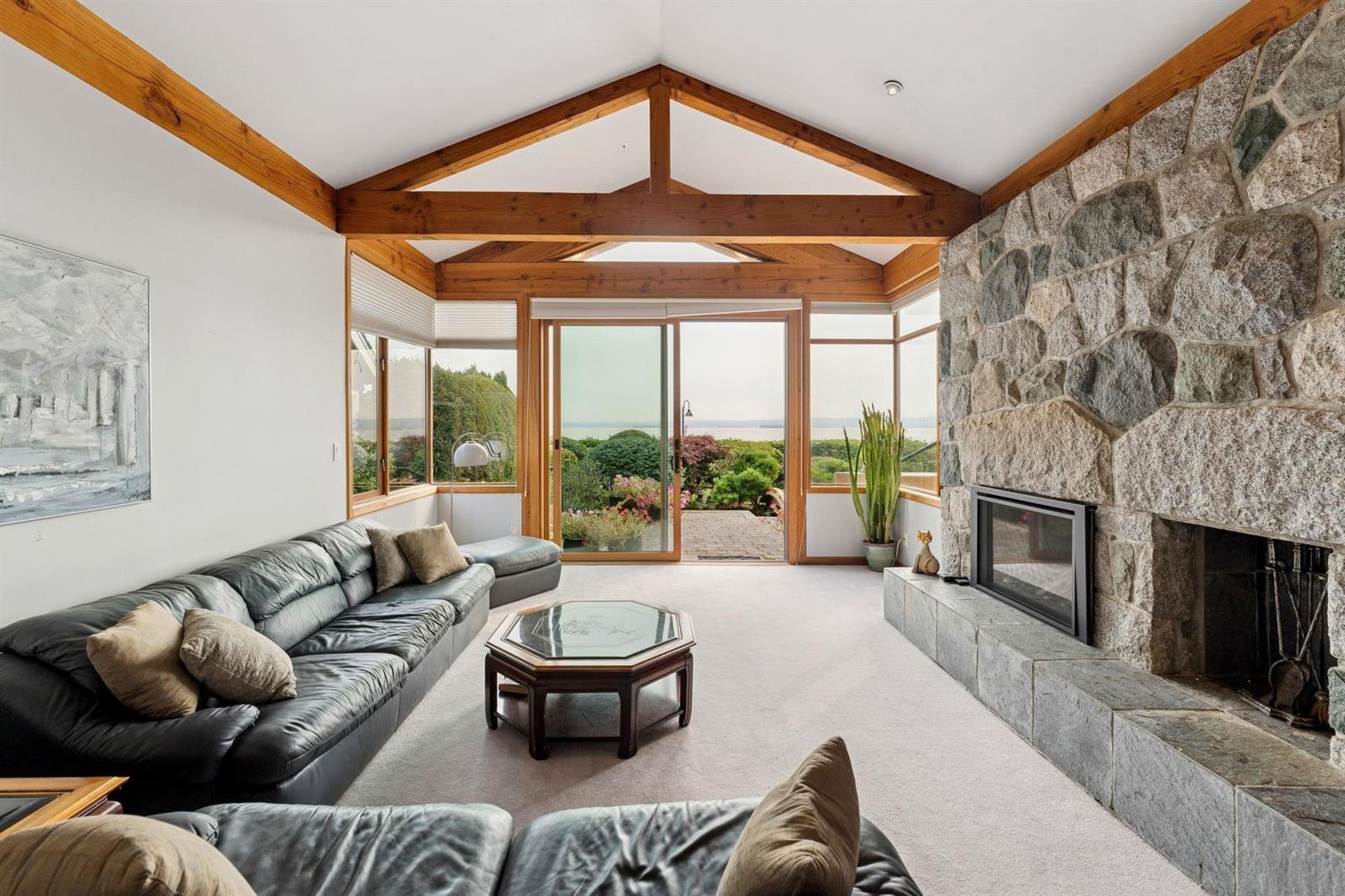 The living room corner, the stone chimney breast and the glass turning to the garden.