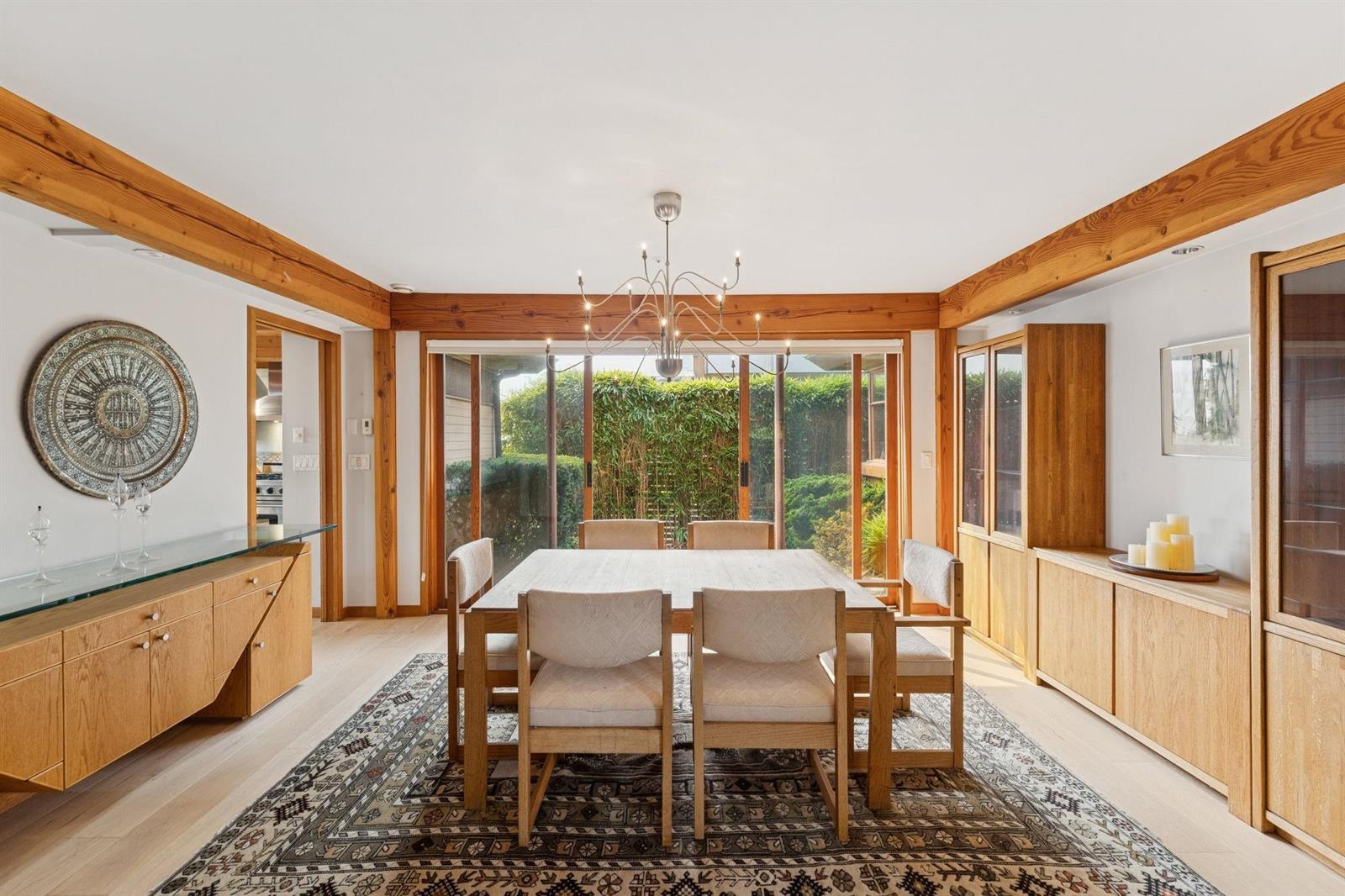 The dining room under a chandelier, the table set beneath a run of windows.