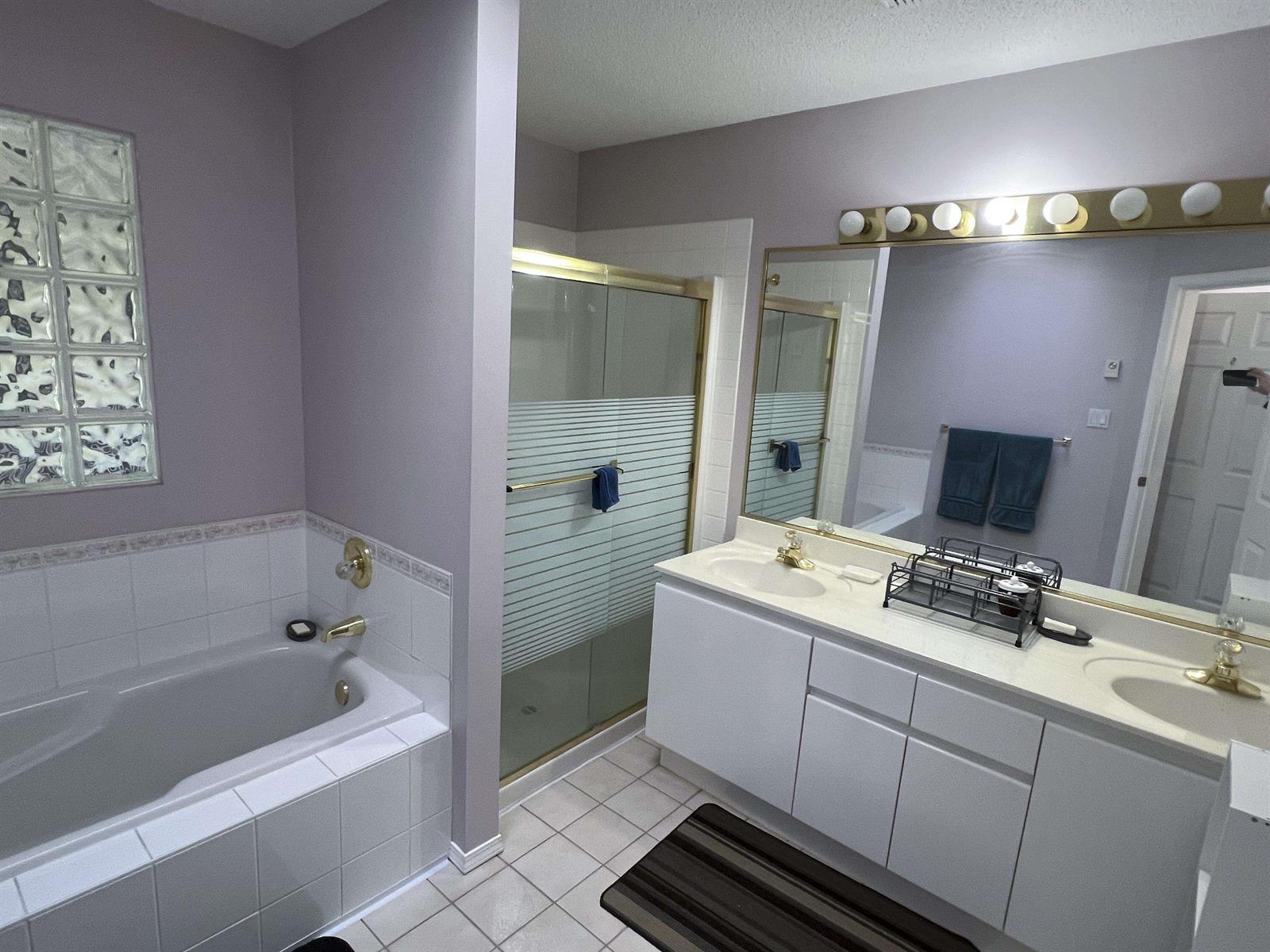 The ensuite, a soaking tub beside a glazed shower with a long mirrored vanity.