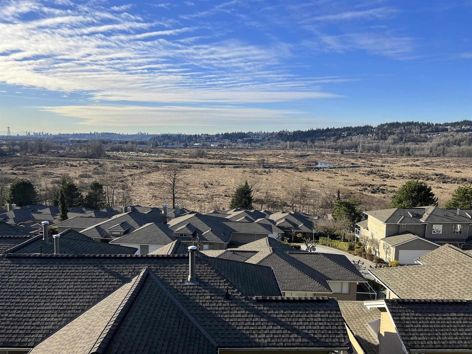 The wider view, the roofs of the complex in the foreground and the Colony Farm flats running out to the hills.