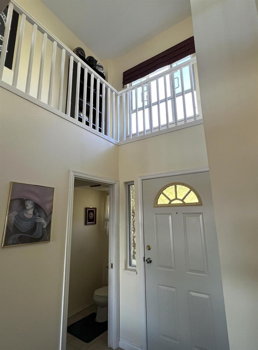 The entry, double height, with the upper landing and its balustrade above the front door.