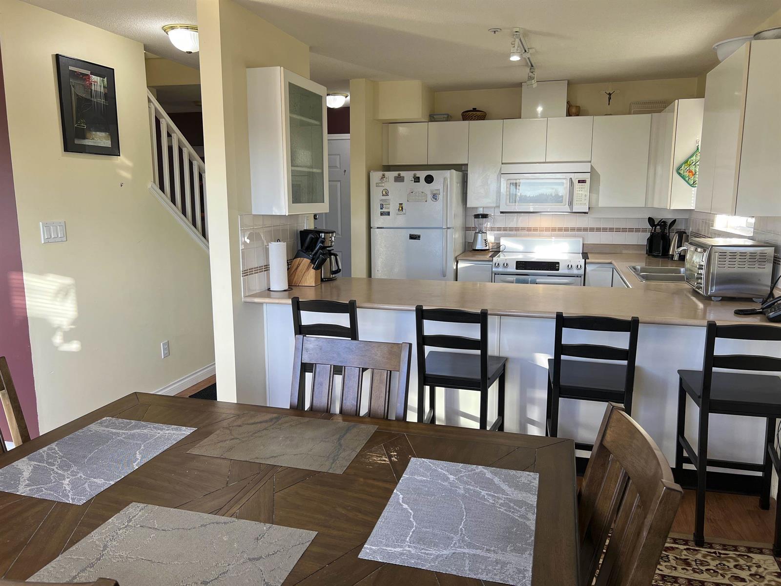 The kitchen from the dining end, the stair rising at the left.