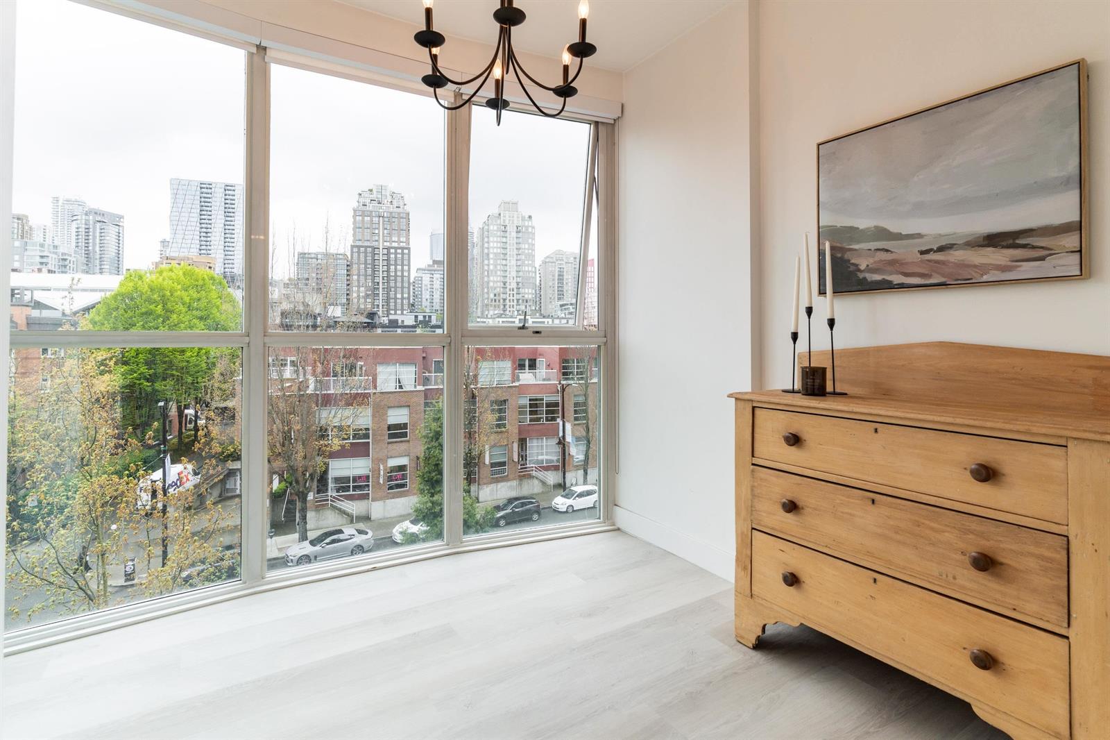 The second bedroom's corner window, a chandelier above and the towers of Yaletown across the street.
