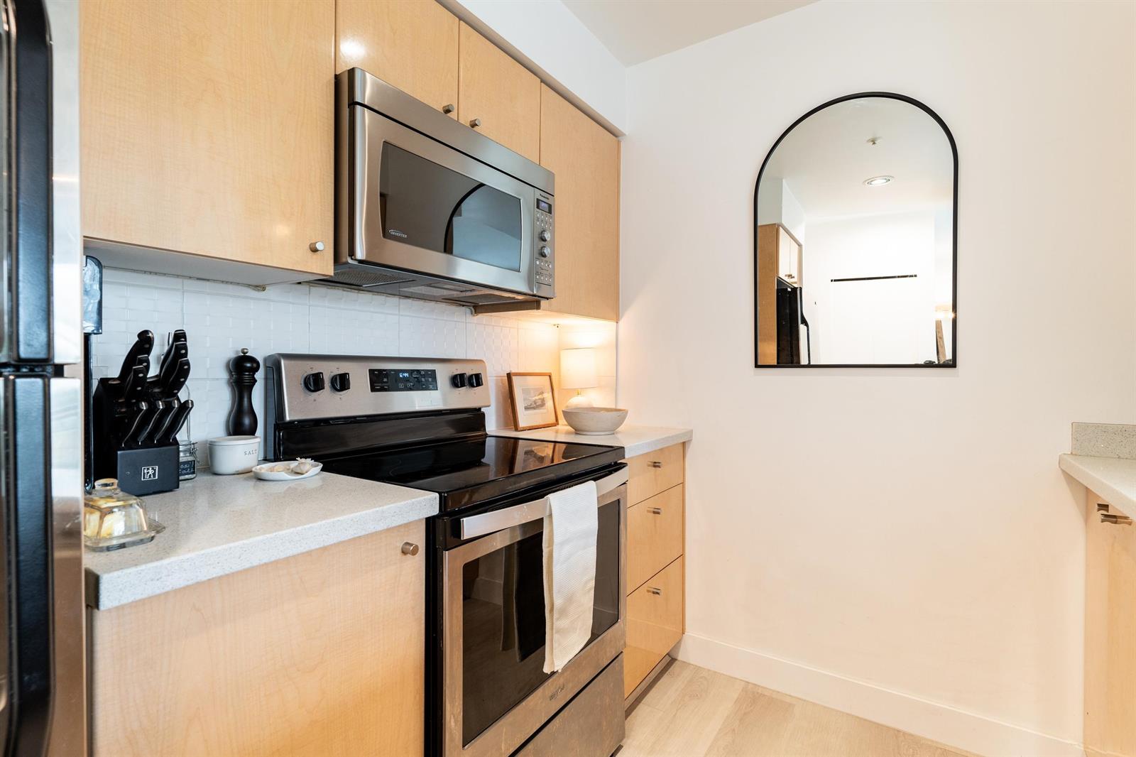 The stainless range and microwave against the maple cabinets, a knife block on the counter.